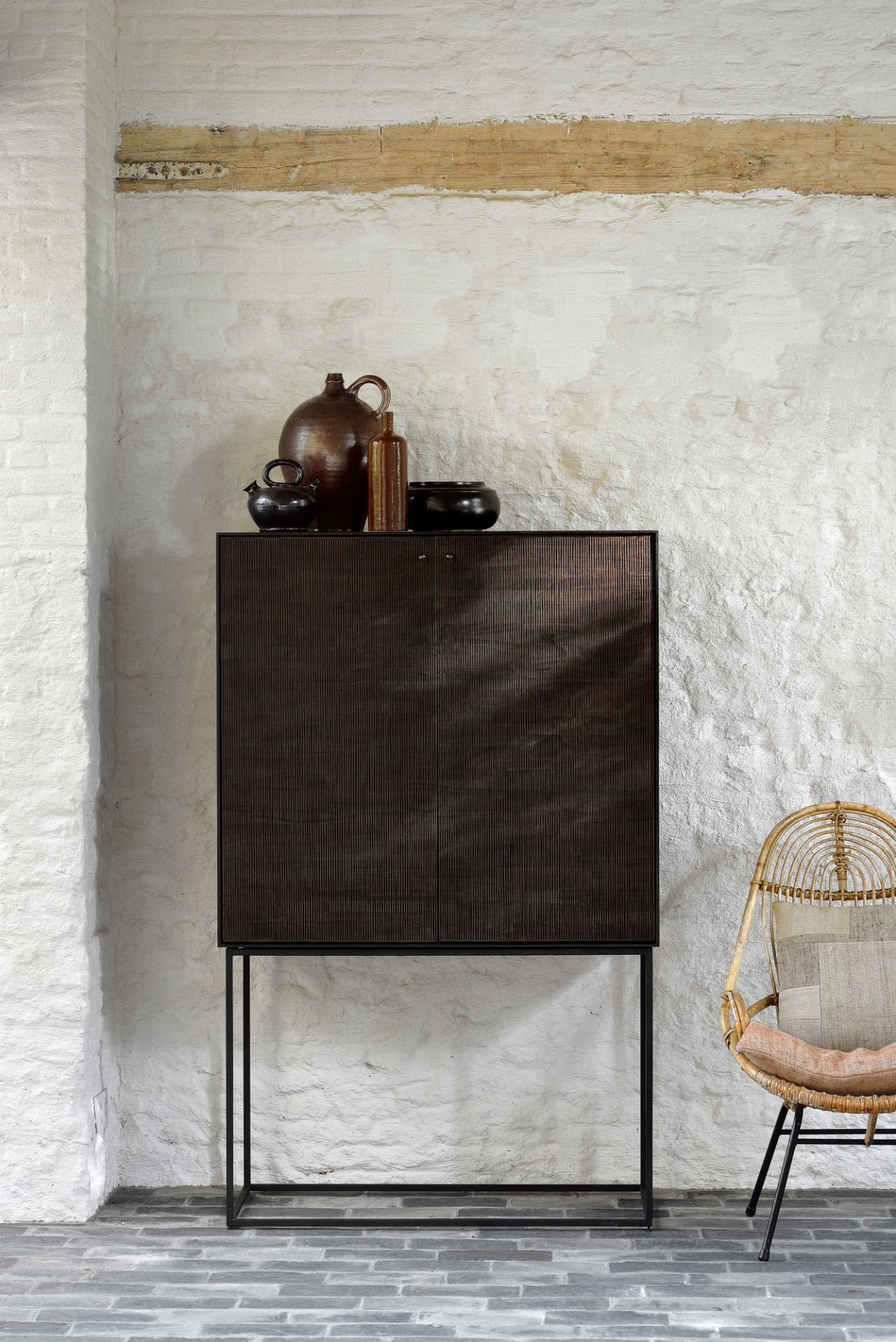 Ethnicraft Teak Grooves Schrank: Moderner Holzschrank mit gerillten Türen und minimalistischem Metallgestell vor weißer Wand.