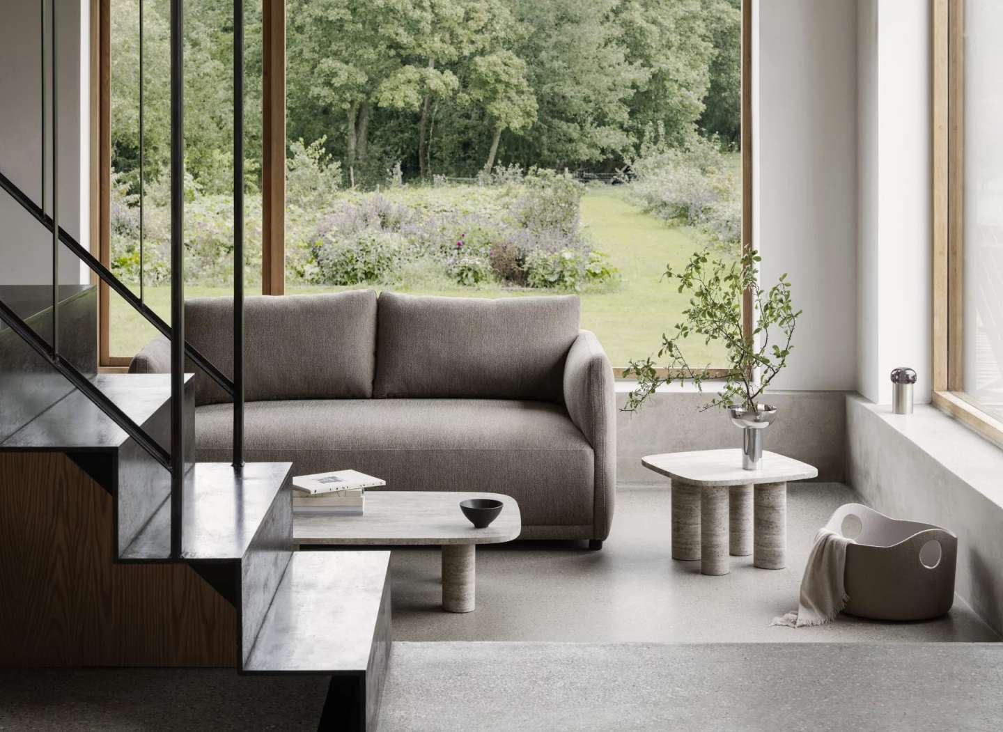 Blomus Volos Couchtisch aus Travertin im Wohnzimmer mit Sofa und Fenster zum Garten.