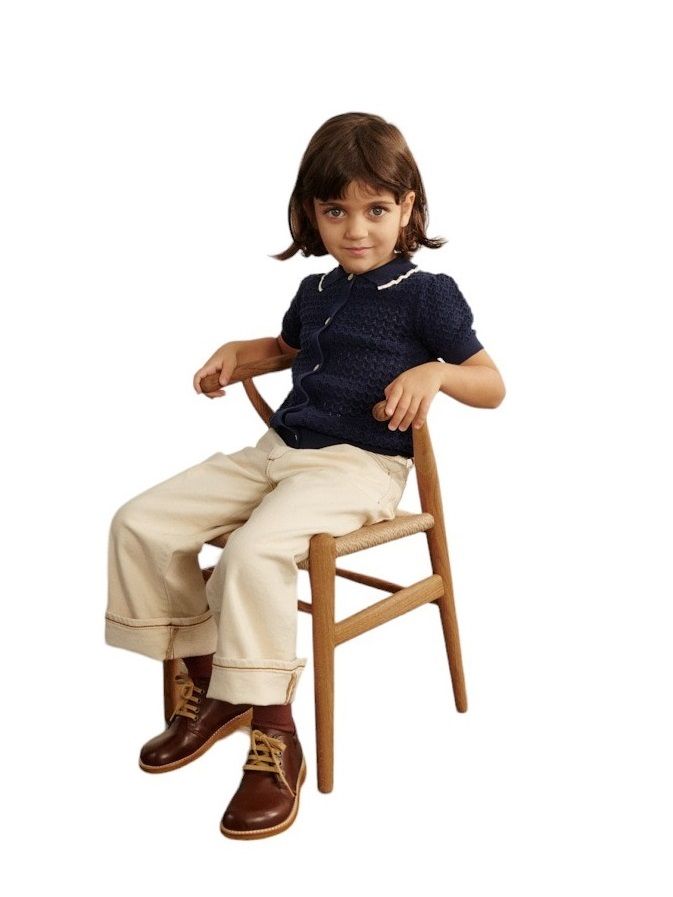 Mädchen sitzt auf einem CH24 Wishbone Stuhl von Carl Hansen & Søn. Kinderstuhl aus Holz.