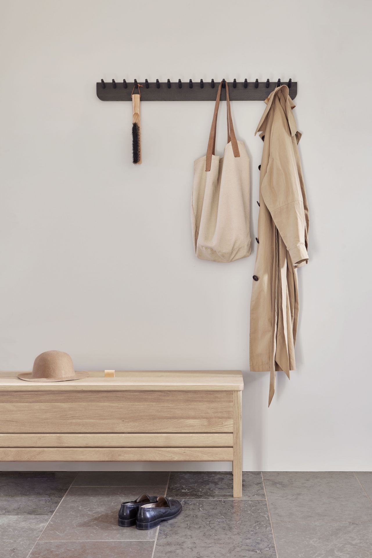 Echo Garderobenleiste Eiche von Form & Refine mit Kleidung, Tasche und Bank.