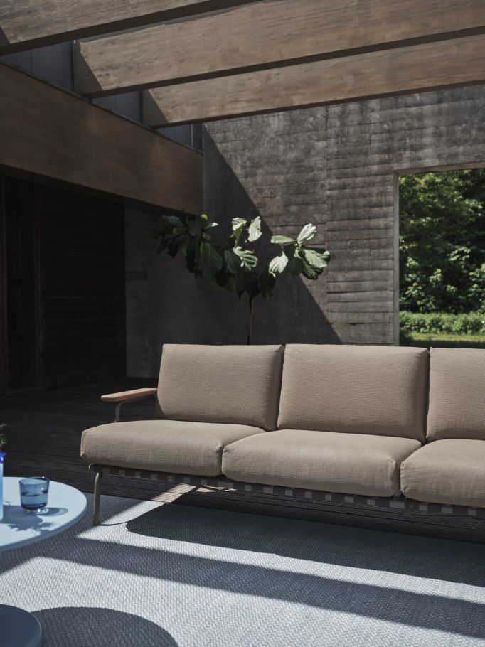 Settle Sofa: Muuto 3-Sitzer Outdoor Sofa in Beige mit Holzarmlehnen auf Terrasse.