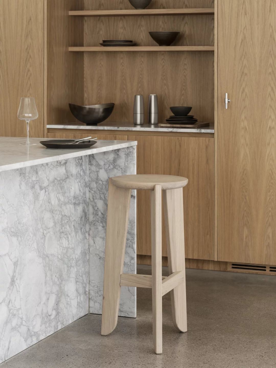 Blomus Eli Barhocker aus hellem Holz vor Marmor-Kücheninsel. Moderner Barstuhl für die Küche.