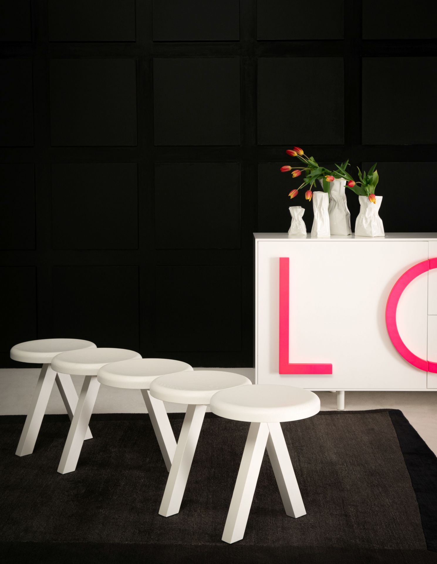 Weiße Millepiedi Bank von Driade vor schwarzer Wand und modernem Sideboard. Design Möbel.