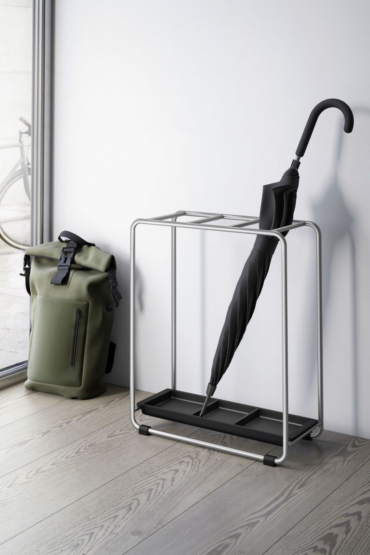 Moderner Mecor Schirmständer ZACK mit schwarzem Schirm und Rucksack im Flur. Metall Schirmhalter.