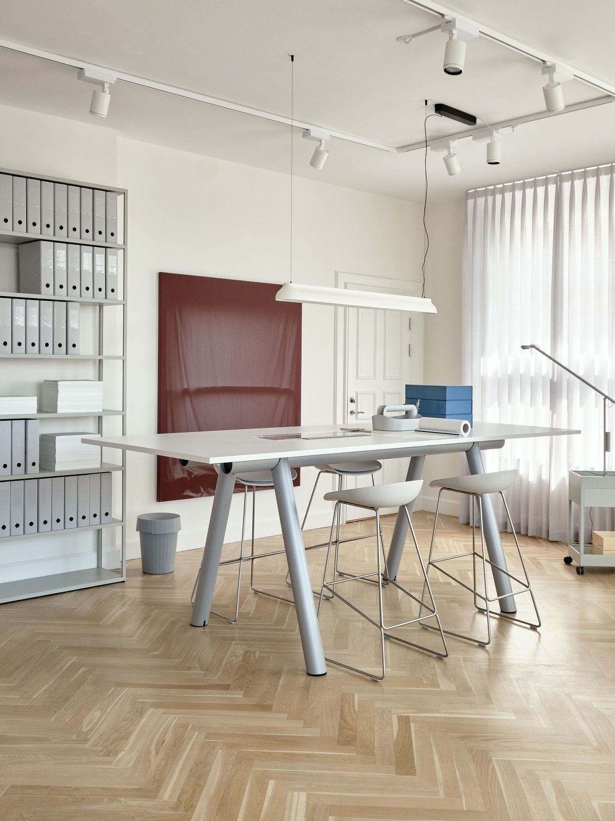 Heller Raum mit dem großen, weißen Hay Boa Table Tisch und grauen Barhockern.