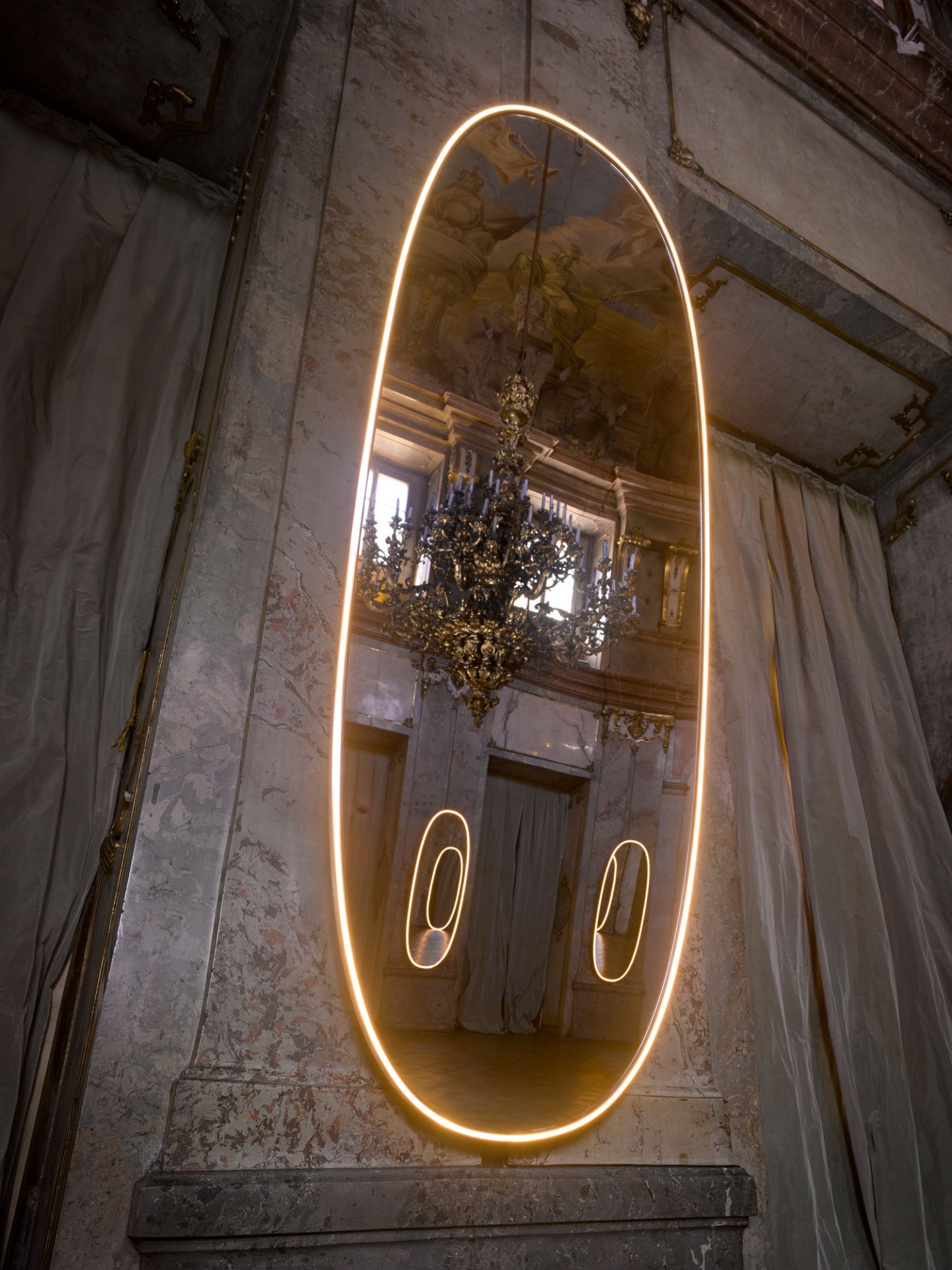 La Plus Belle Wandleuchte von Flos: Ovaler Lichtspiegel mit Aluminiumrahmen und warmem LED-Licht.