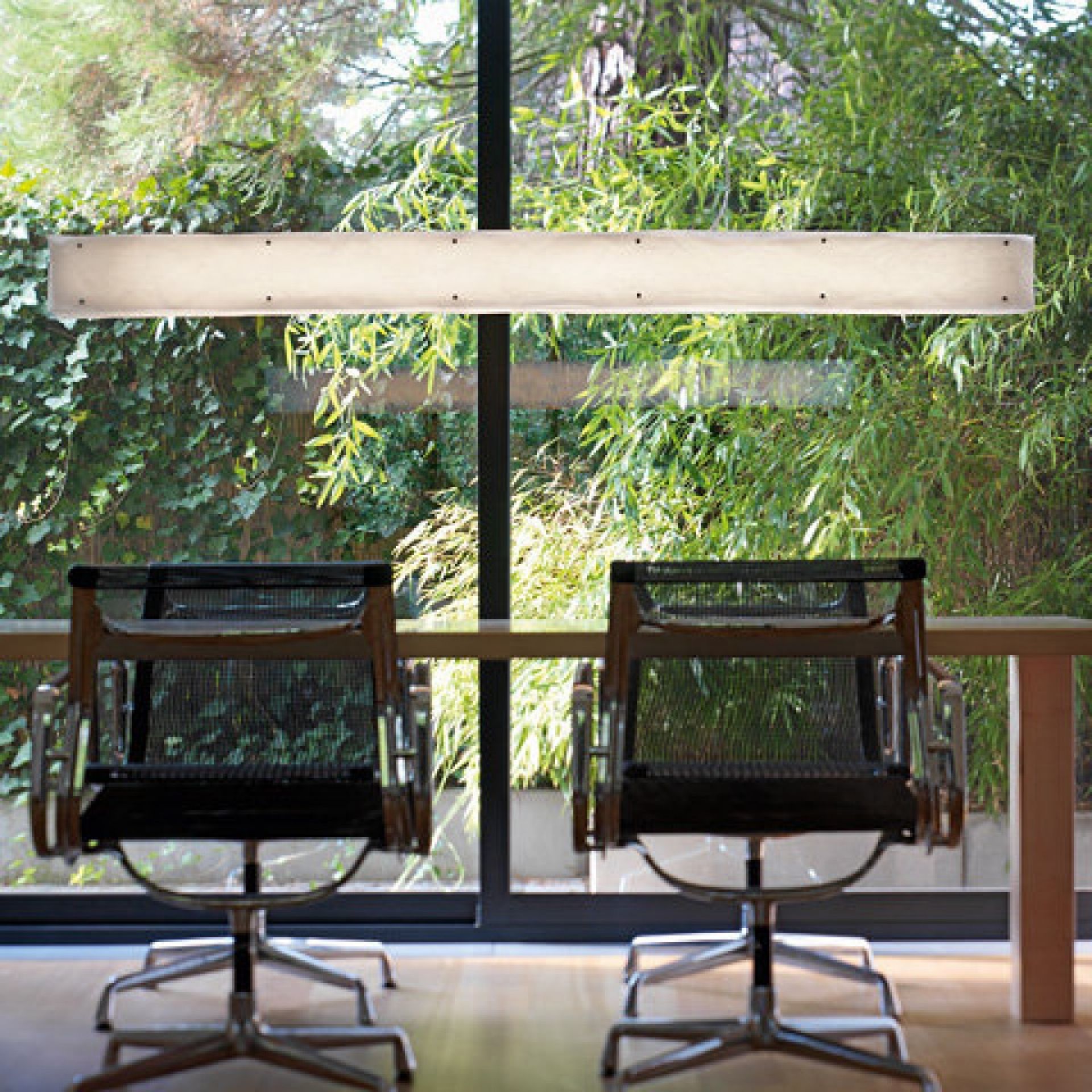 One by One Pendelleuchte von Belux, längliche Deckenleuchte über einem Tisch mit Stühlen.