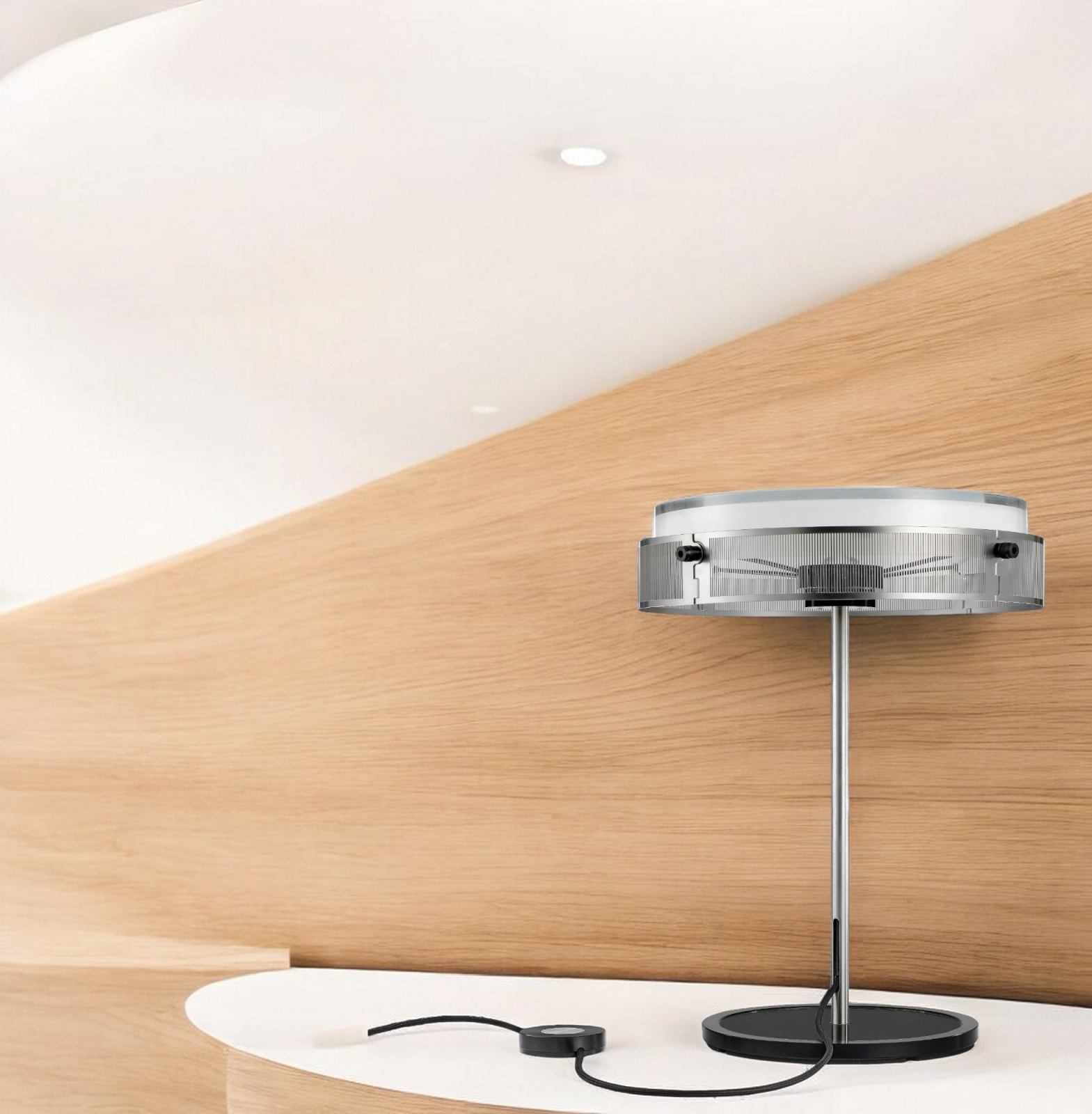 Anima Tischleuchte Lumina: Moderne Tischlampe mit silbernem Gestell und rundem Lampenschirm auf weißem Tisch.