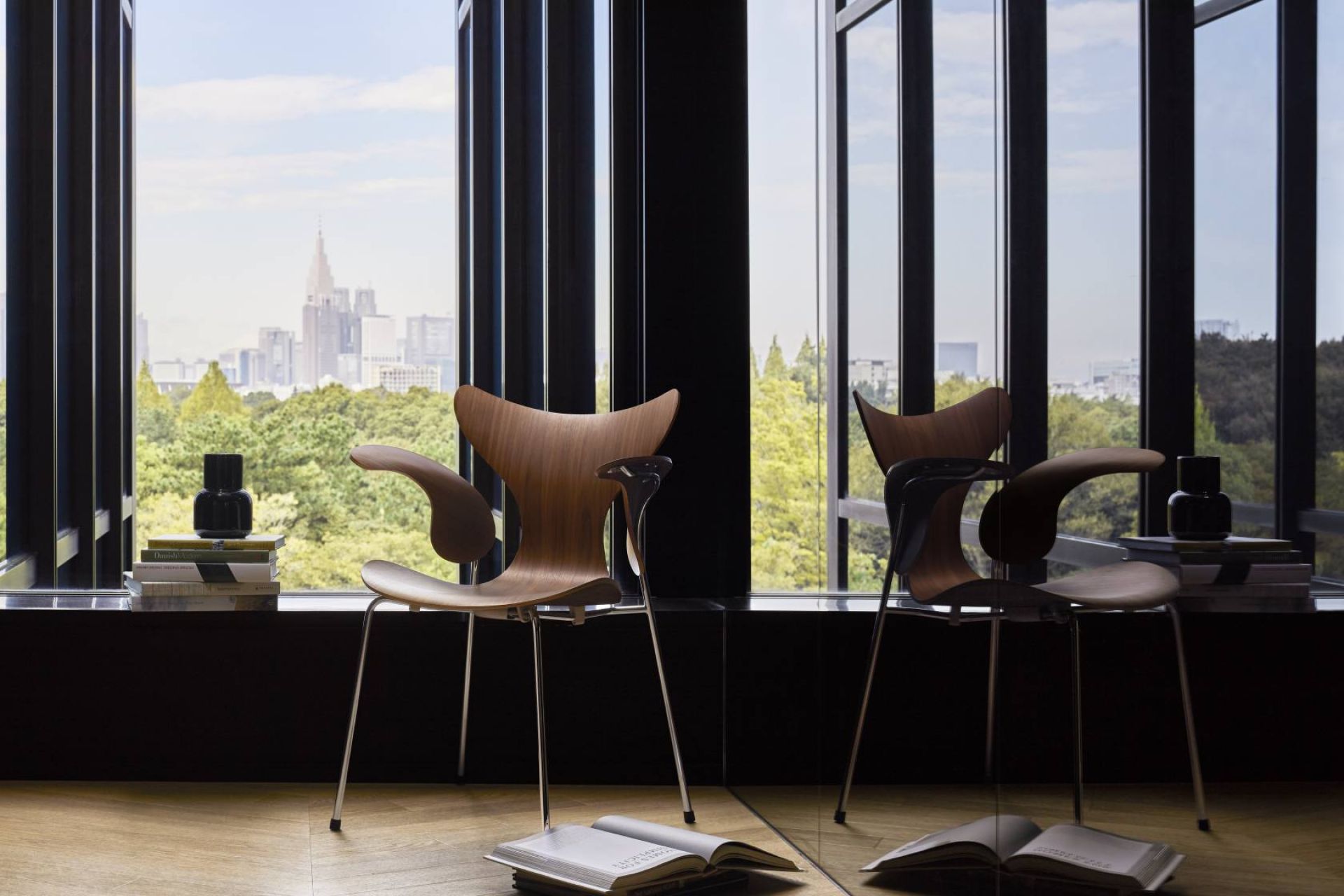 Lily Armlehnenstuhl von Fritz Hansen: Holzstuhl mit Armlehnen vor Fenster mit Stadtblick. Designklassiker.