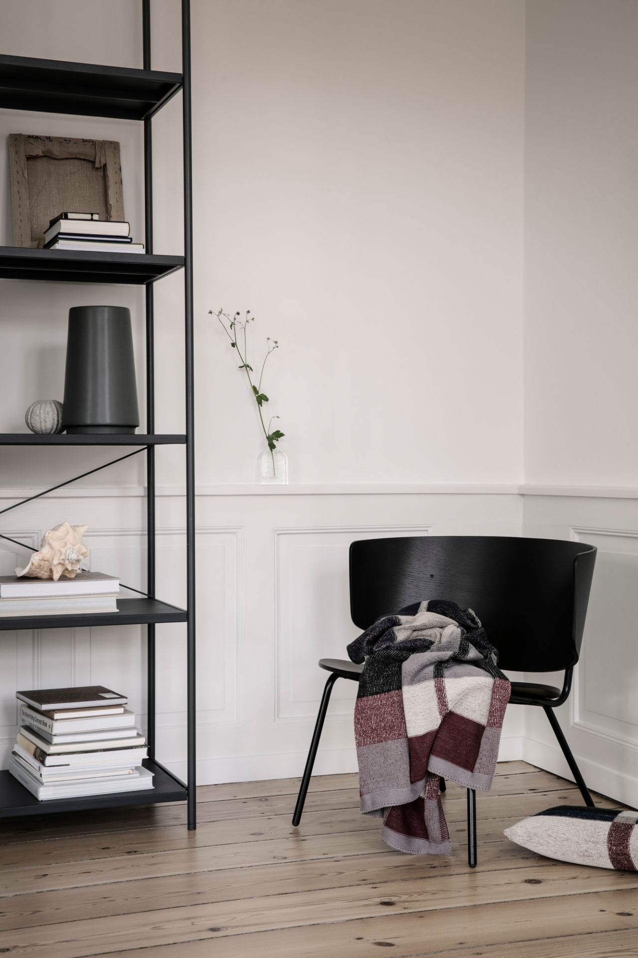 Schwarzes Punctual Shelving System 1x5 von Ferm Living mit Deko-Objekten und einem Stuhl im Raum.