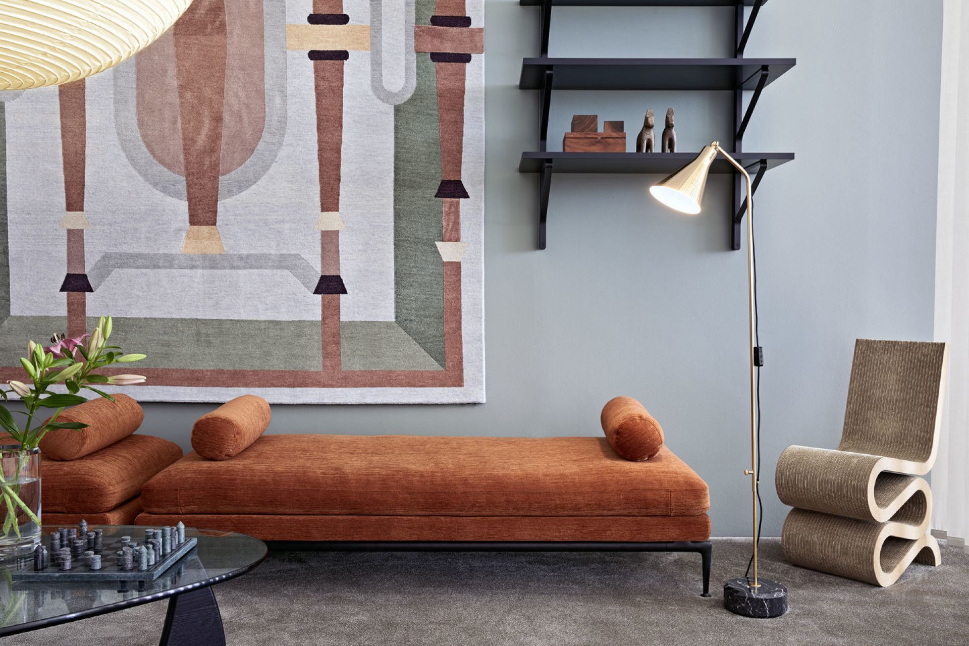 Innenaufnahme eines Wohnzimmers mit Vitra Wiggle Side Chair Stuhl aus Pappe neben einer Liege.