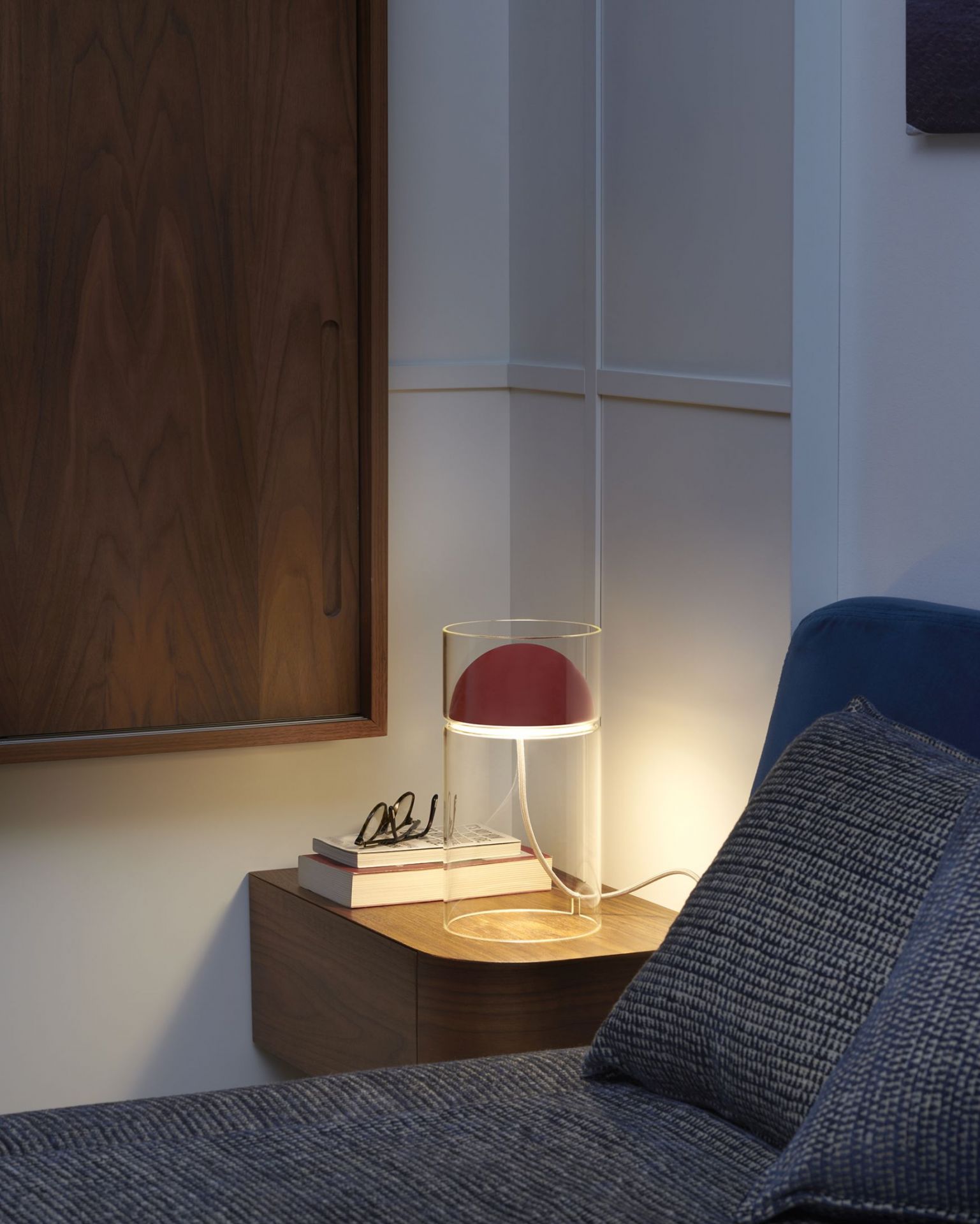 Medusa Tischleuchte von Oluce: Moderne Lampe mit rotem Schirm und Glaszylinder auf Nachttisch.