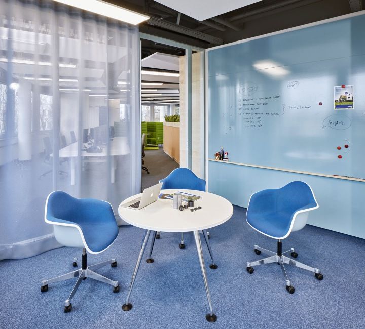 Vitra Eames Plastic Arm Chair DAL, vollgepolstert, in blau, mit Chromgestell an kleinem Tisch.