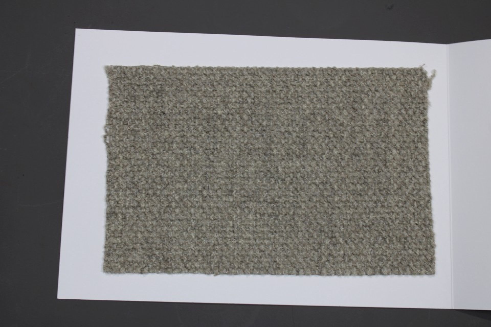 Stoffmusterkarte Cor Gruppe 82: Nahaufnahme eines grauen, melierten Möbelstoff-Musters auf weißem Karton.
