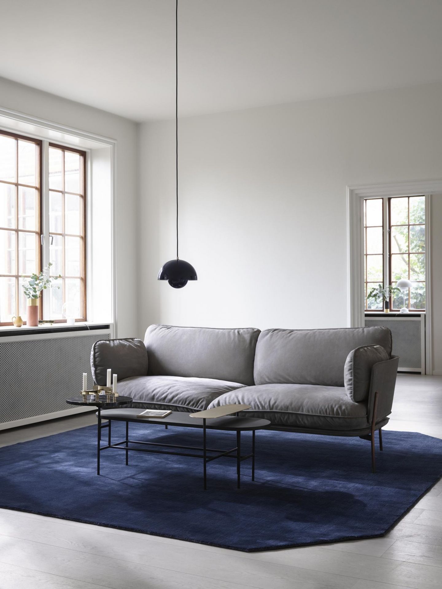 AndTradition Palette Table JH7 Couchtisch im Wohnzimmer mit grauer Couch und blauem Teppich.