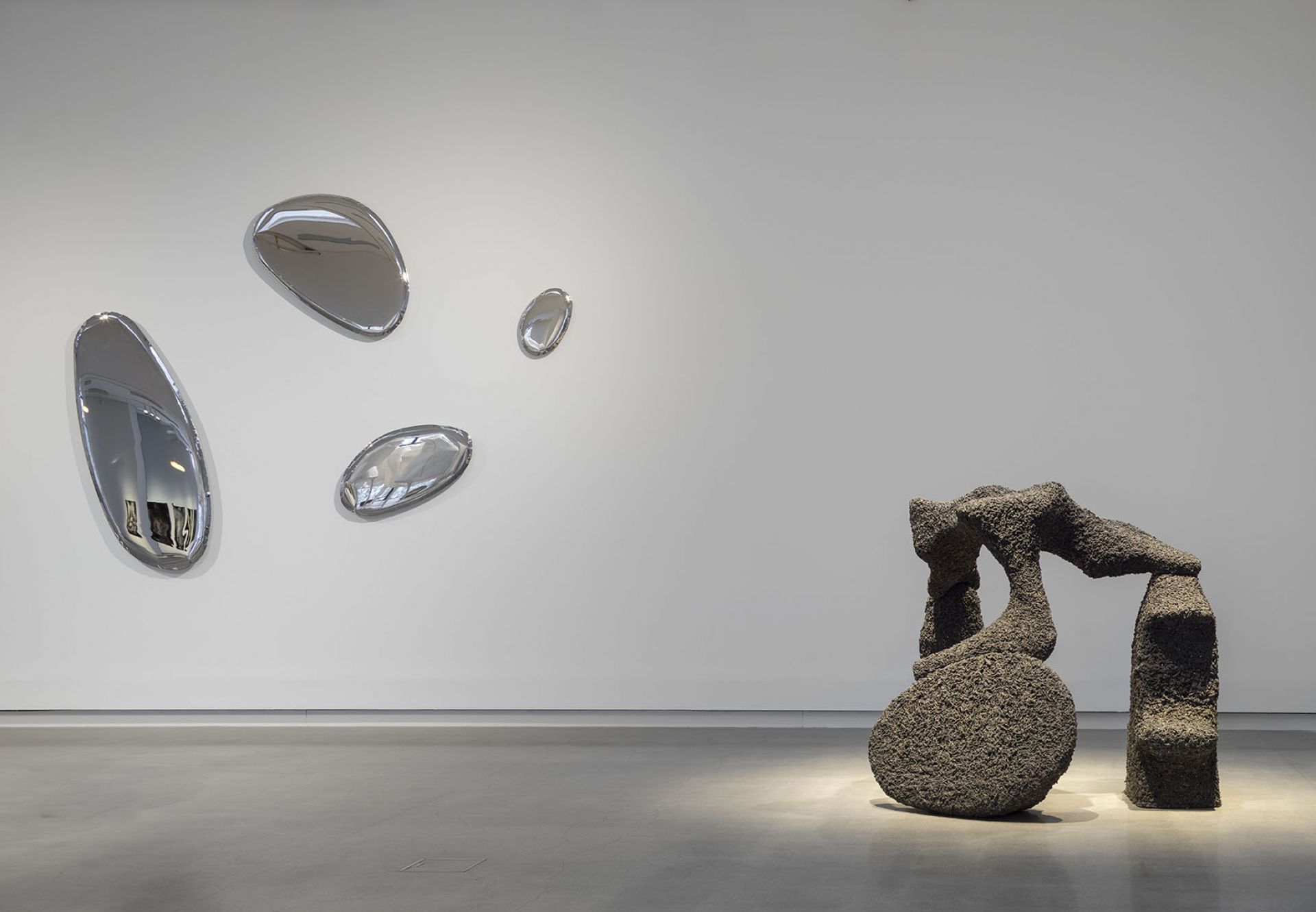 Tafla Spiegel von Zieta: Mehrere tropfenförmige, silberne Wandspiegel in einem minimalistischen Raum.