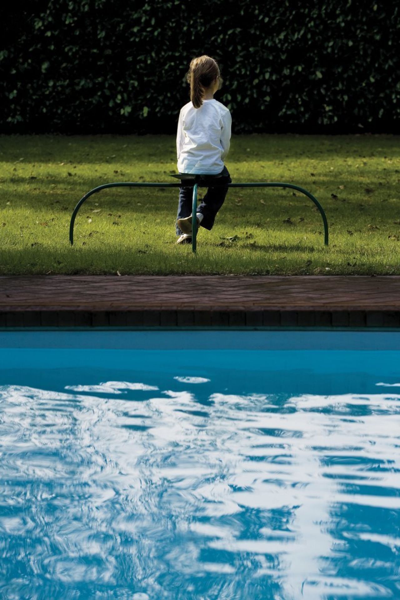 Mädchen sitzt auf Zanotta Allunaggio Stuhl im Garten am Pool, modernes Outdoor Möbel.