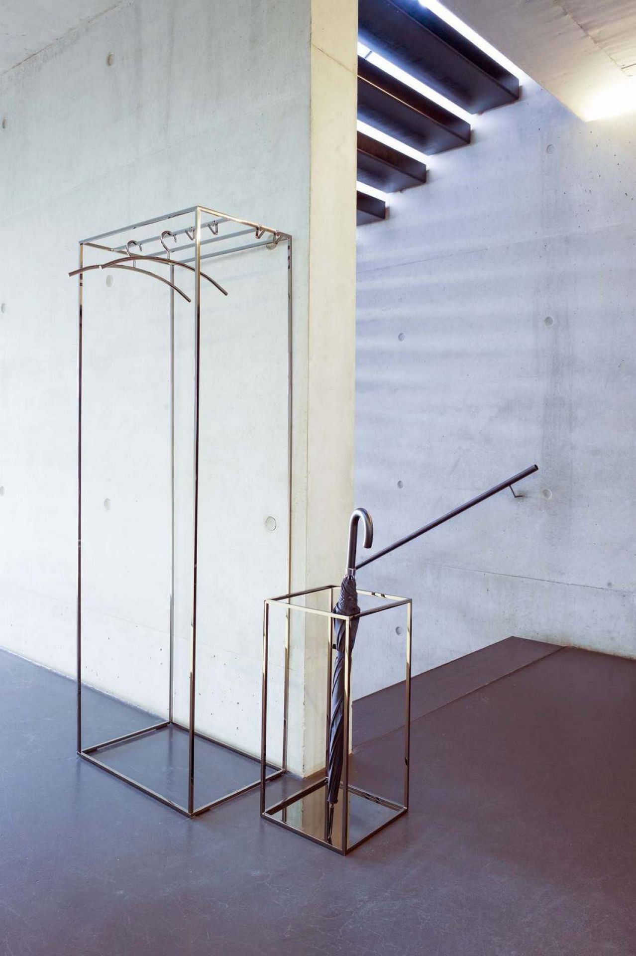 Schönbuch Rack: Moderner Schirmständer und Beistelltisch aus Metall mit Schirm und Kleiderbügel.