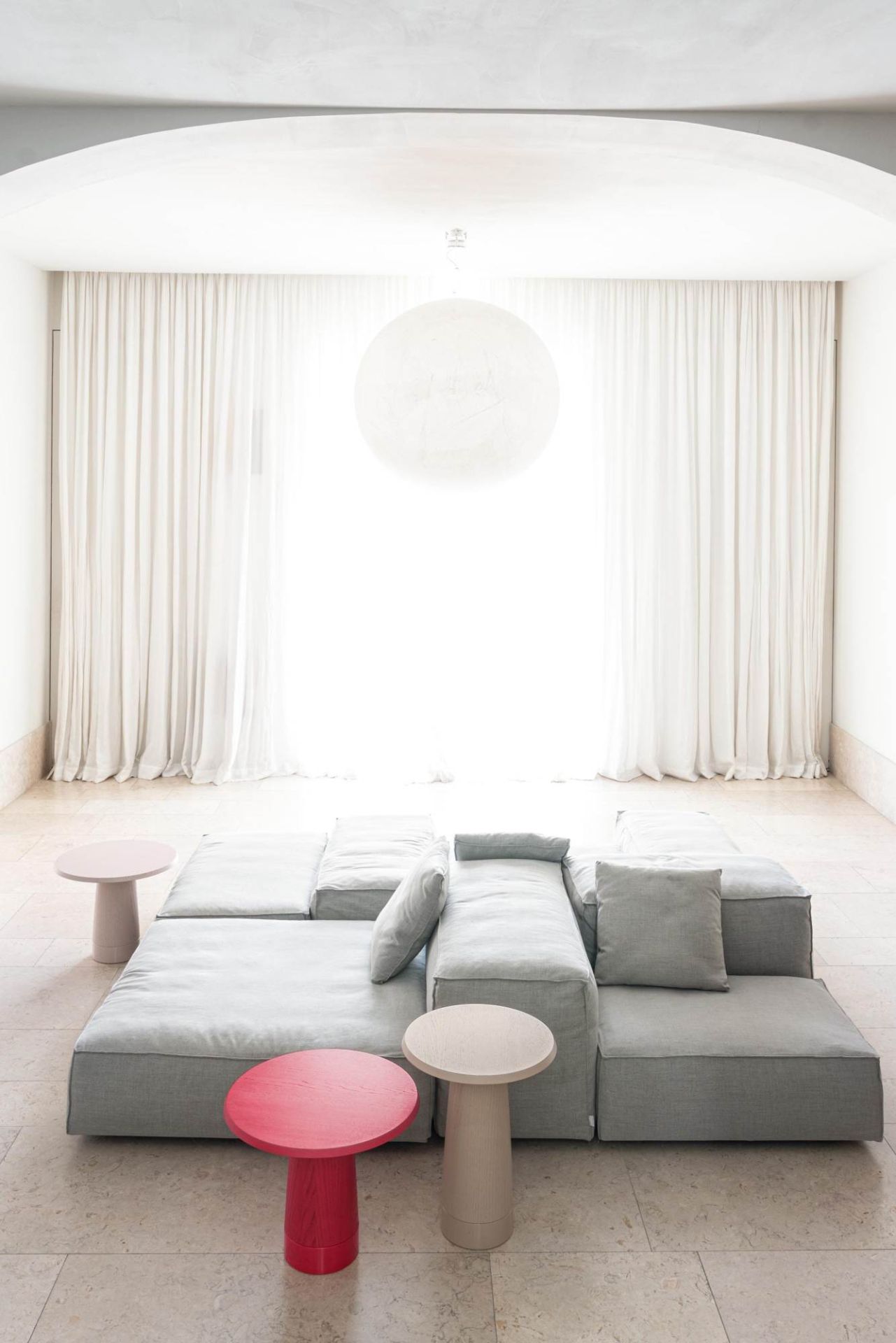 Wohnzimmer mit modularem Sofa und drei Schönbuch Amanita Beistelltischen in Rot, Beige und Rosa.