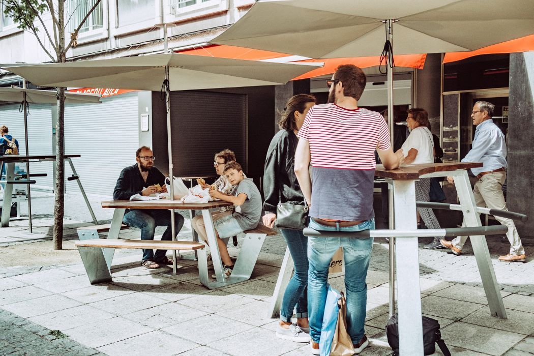 Menschen sitzen unter Extremis Sonnenschirmen im Freien und genießen die schattige Atmosphäre.