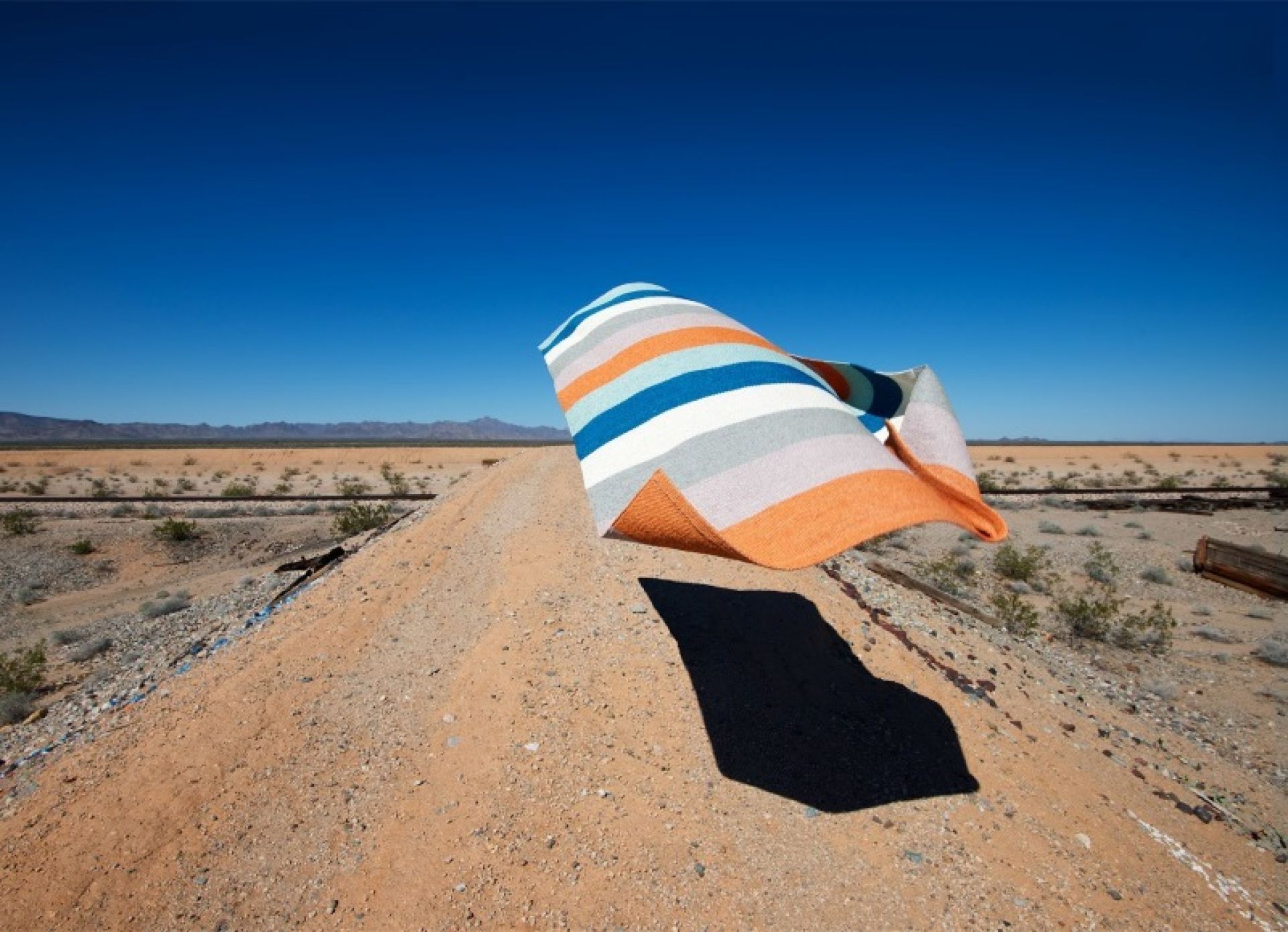 Musterbild: Pappelina Molly Kunststoffteppich FOREST mit Streifenmuster in Wüstenlandschaft. Outdoor Teppich.