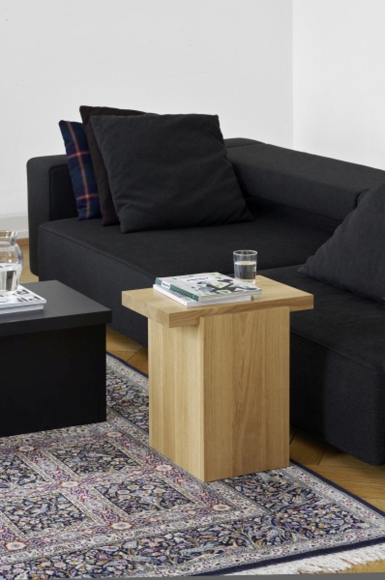 DT02 Tore Small Beistelltisch e15 aus Eiche, neben schwarzem Sofa auf einem Teppich.
