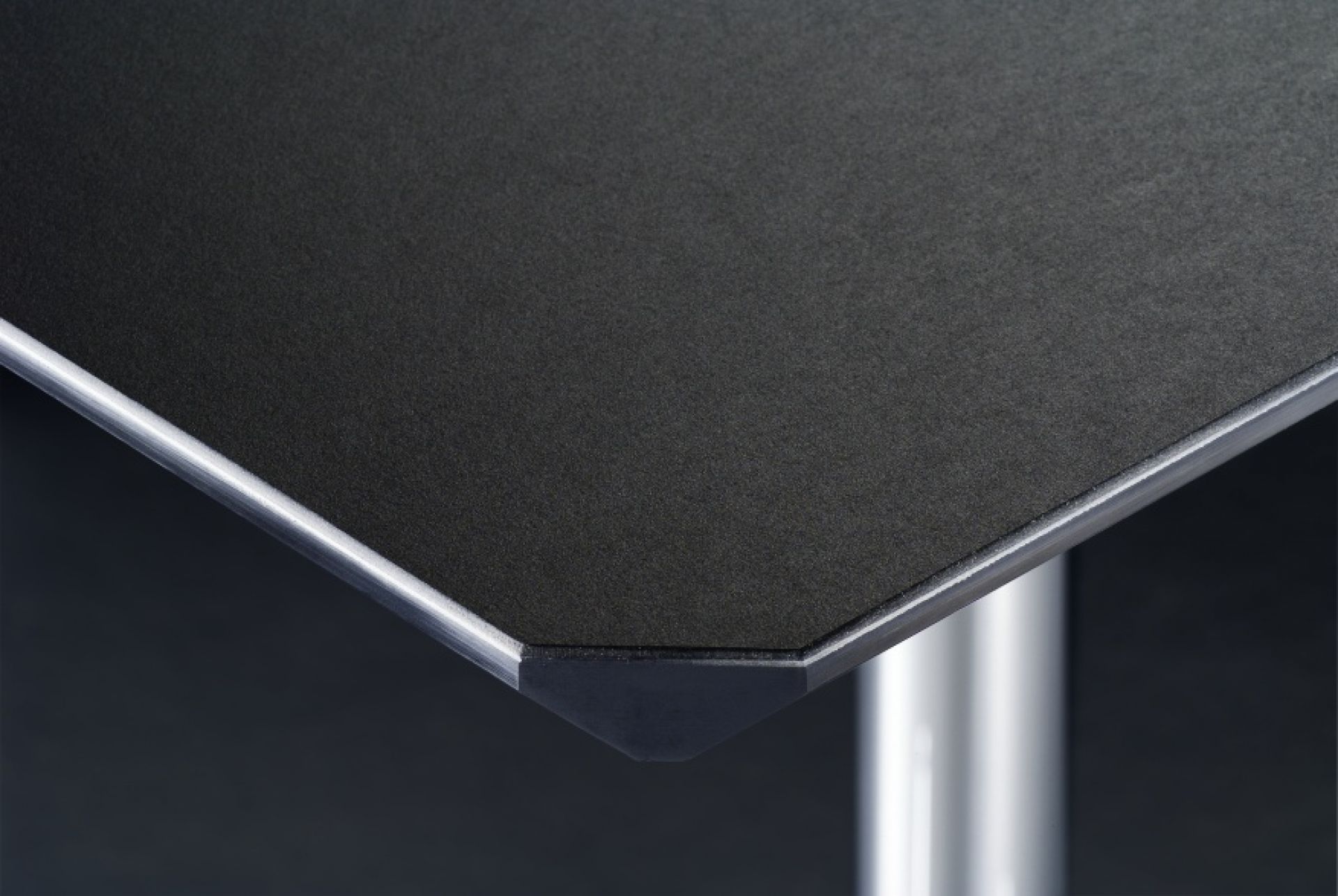 Detailaufnahme USM Haller Kitos M Schreibtisch mit Linoleumoberfläche in Nero und verchromtem Tischbein.