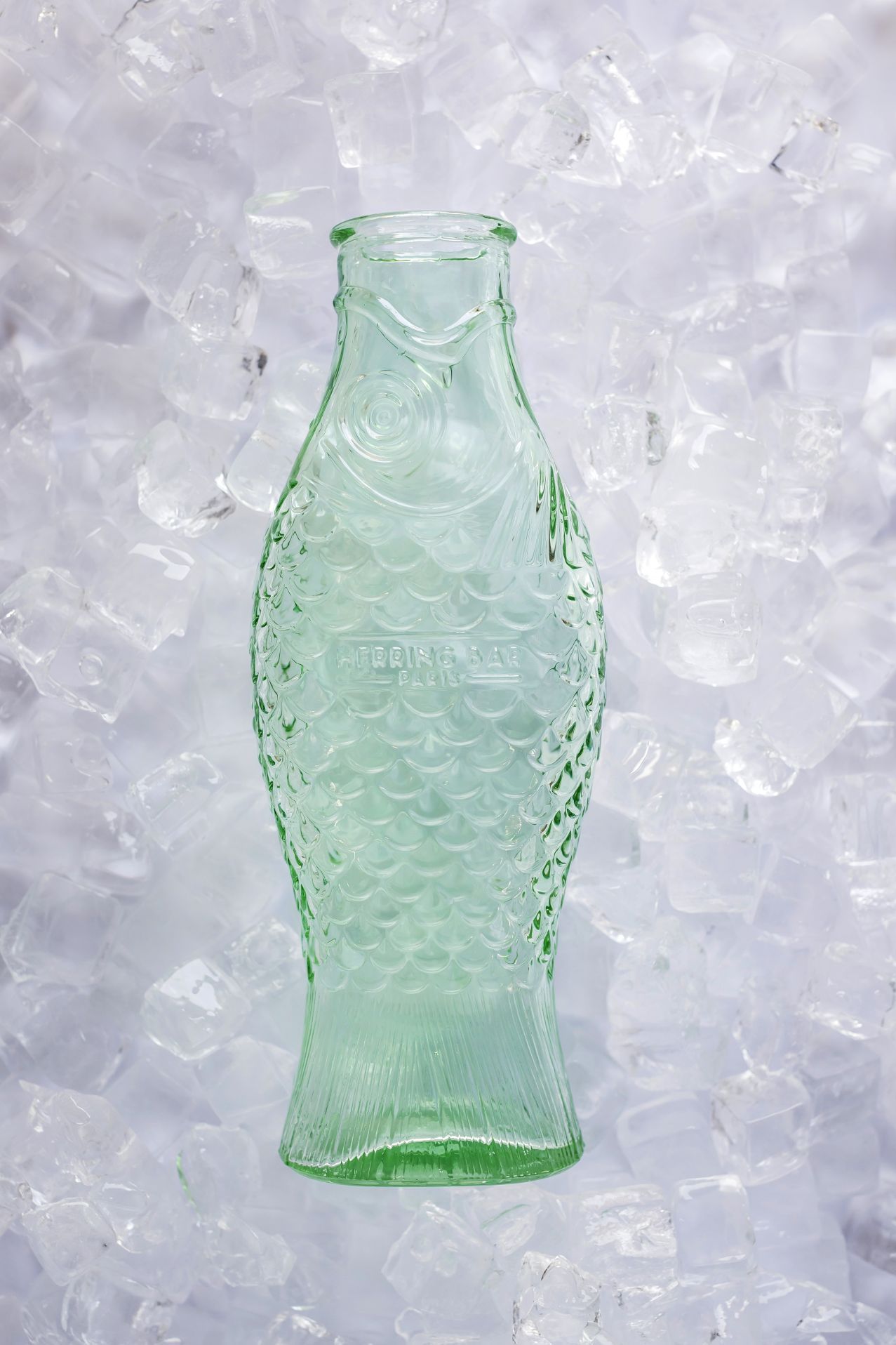 Grüne Fles Flasche in Fischform von Serax auf Eiswürfeln, dekorative Glasflasche für Wasser.