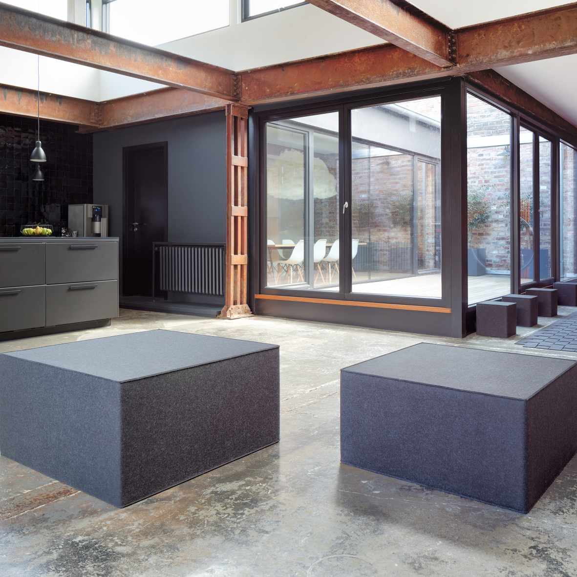 Zwei graue Big Quart Sitzmöbel von Hey Sign in einem modern eingerichteten Raum.