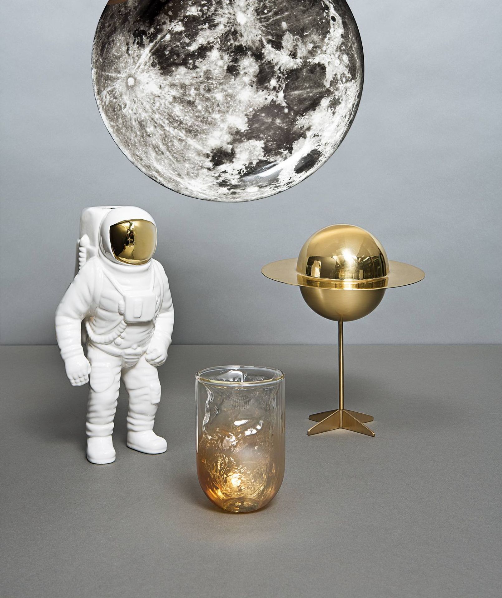 Keramikvase in Astronautenform, goldene Planetenlampe und Glasvase vor Mondlampe. Seletti Starman Vase.