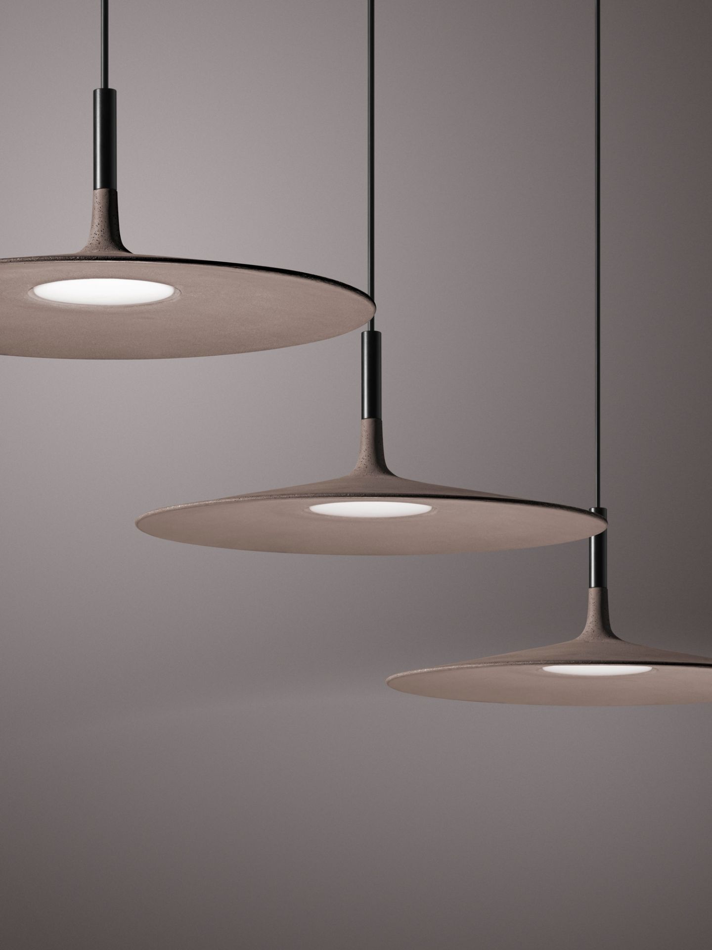 Drei graue Aplomb LED Pendelleuchten von Foscarini mit runder Form und modernem Design.