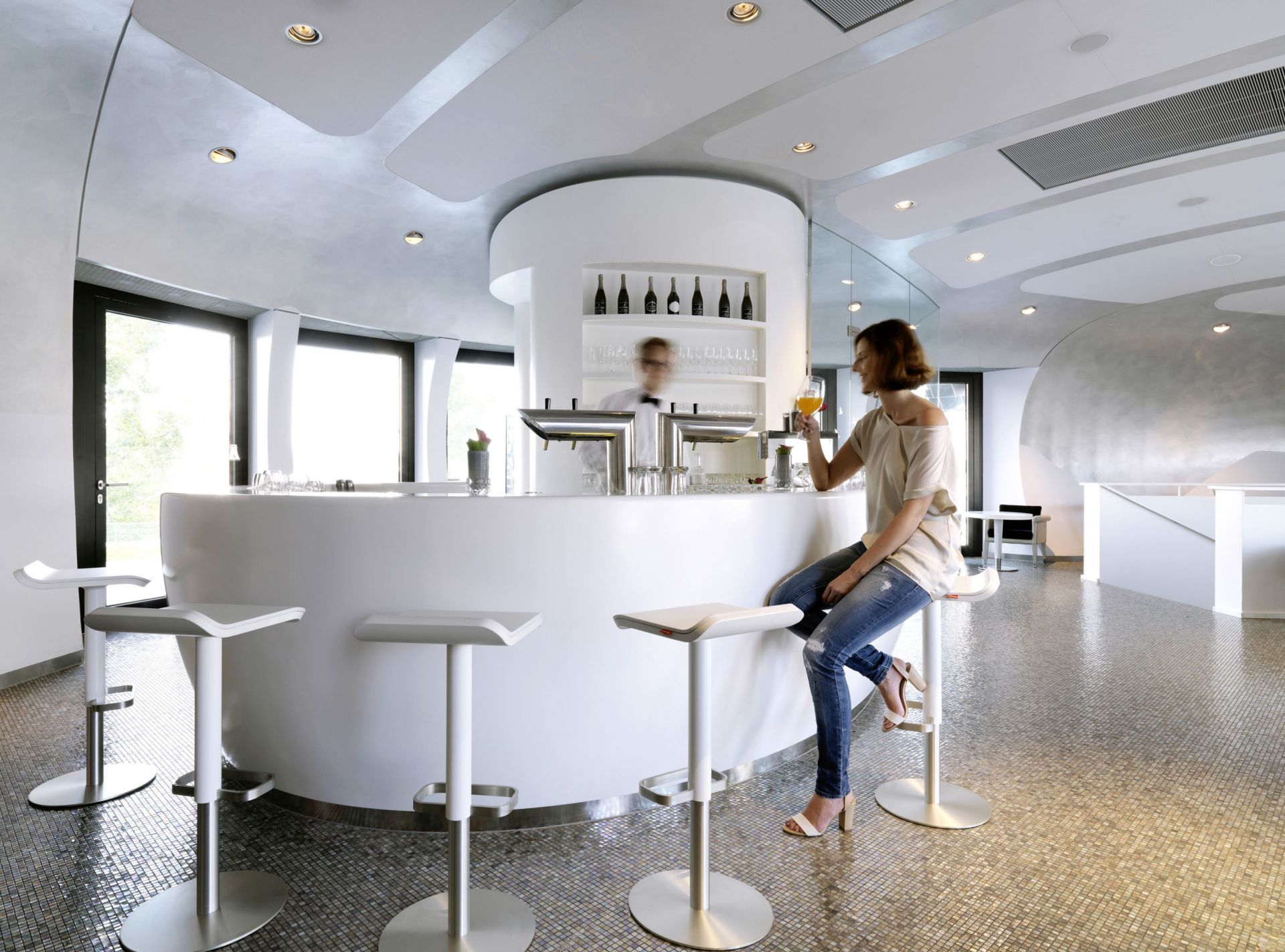 Frau sitzt auf einem weißen, höhenverstellbaren ED Barhocker von Moree an einer Bar.