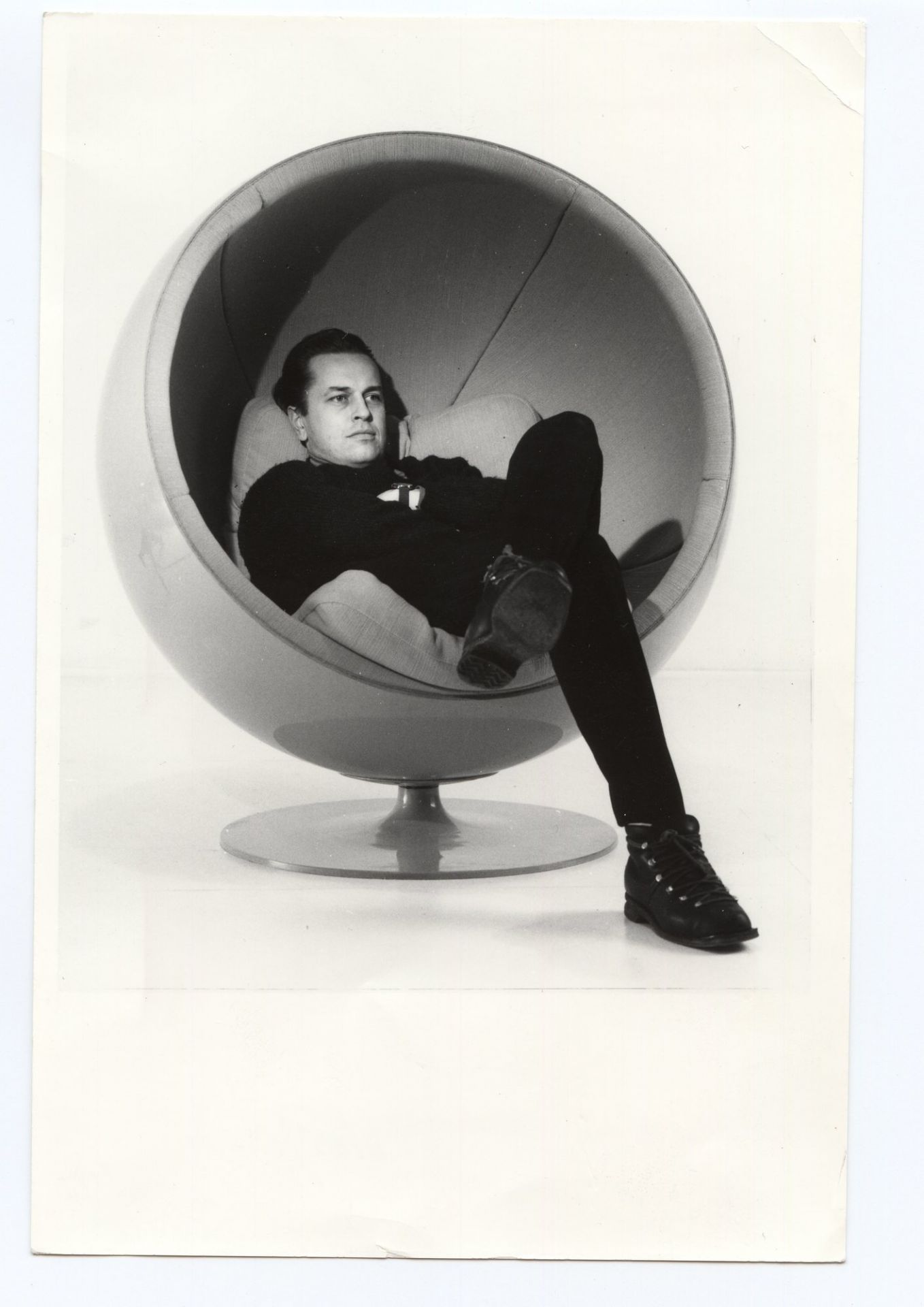 Mann entspannt im grauen Ball Chair Sessel, ein Designklassiker von Eero Aarnio Originals.