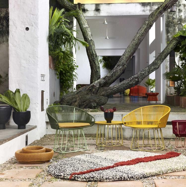 Ames Circo Beistelltisch Outdoor mit bunten Stühlen und Teppich im Garten.