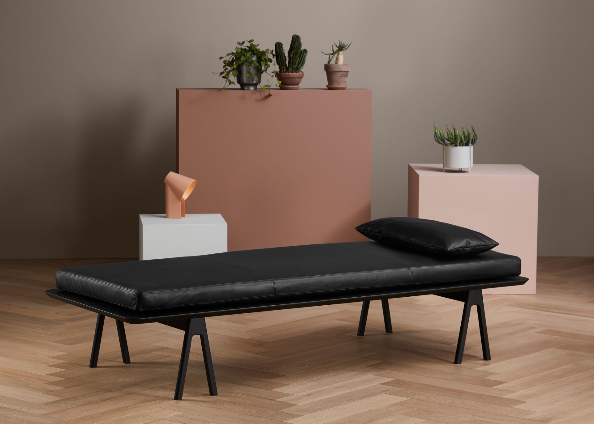 Schwarze Level Daybed Liege von Woud mit Kissen auf hellem Holzboden, modernes Möbeldesign.