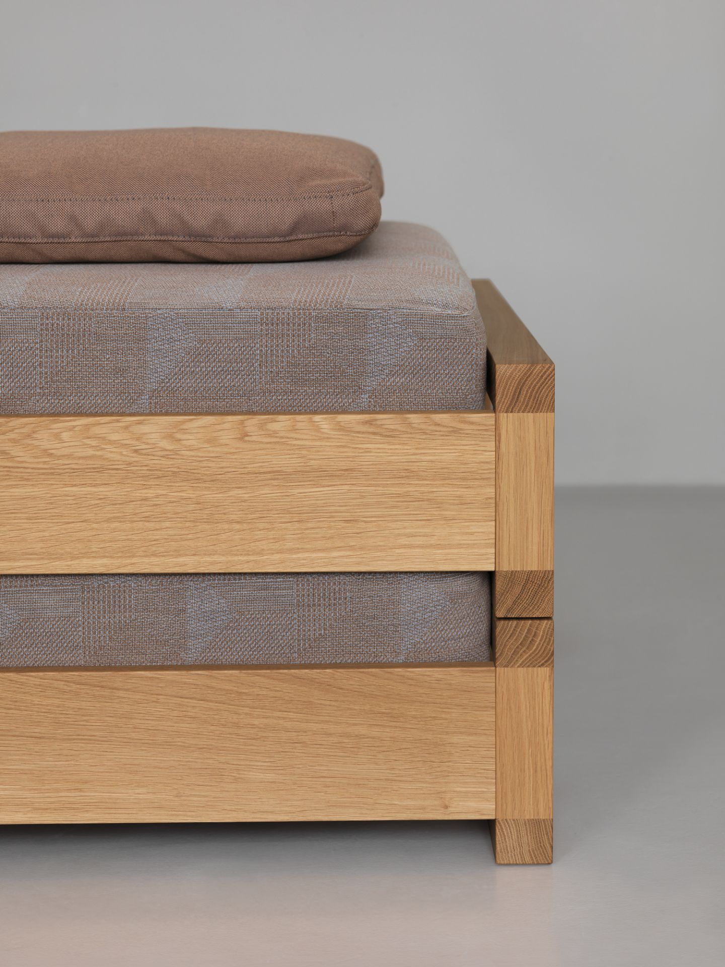 Detailaufnahme vom Guest 90 Holzbett Eiche mit braunem Kissen und Stoffbezug. Massivholzbett für Schlafzimmer.