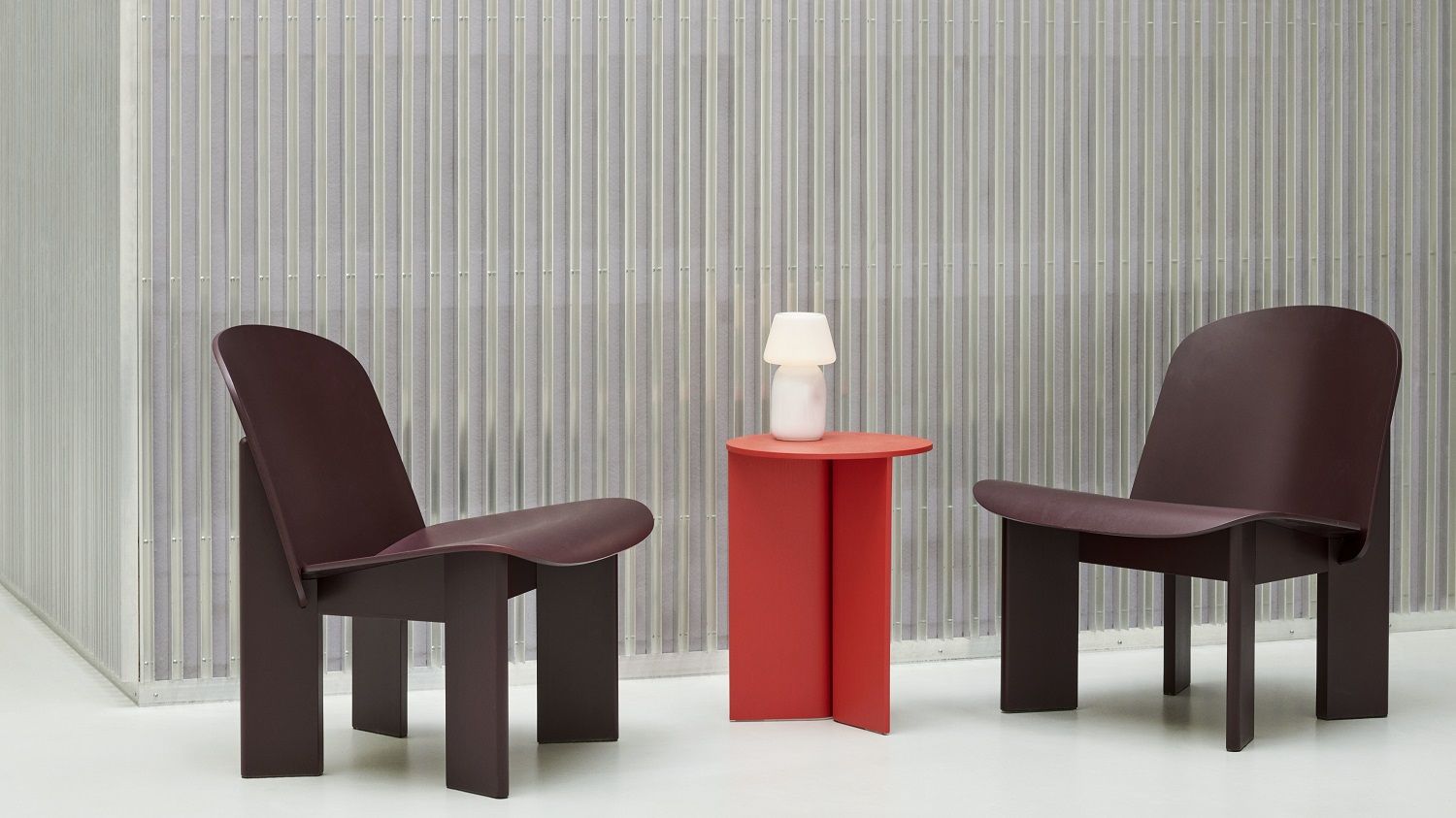 Zwei braune Chisel Lounge Chairs von Hay mit rotem Beistelltisch und Lampe. Modernes Möbeldesign.