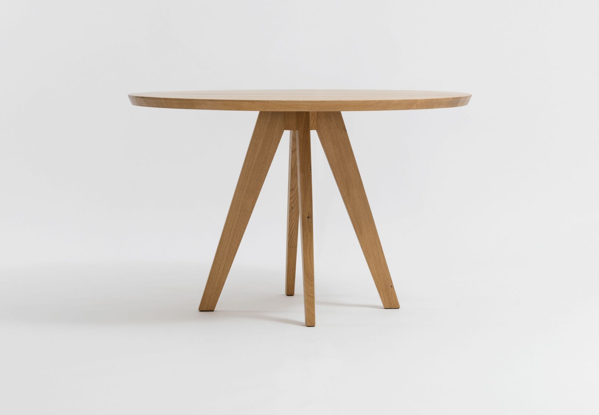 CENA Tisch: Runder Esstisch aus hellem Holz mit drei Beinen vor weißem Hintergrund.