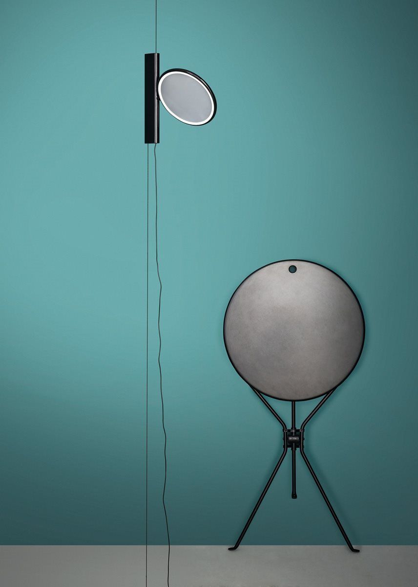 Cumano Klapptisch von Zanotta, zusammengeklappt an Wand gelehnt, mit Wandlampe im minimalistischen Design.