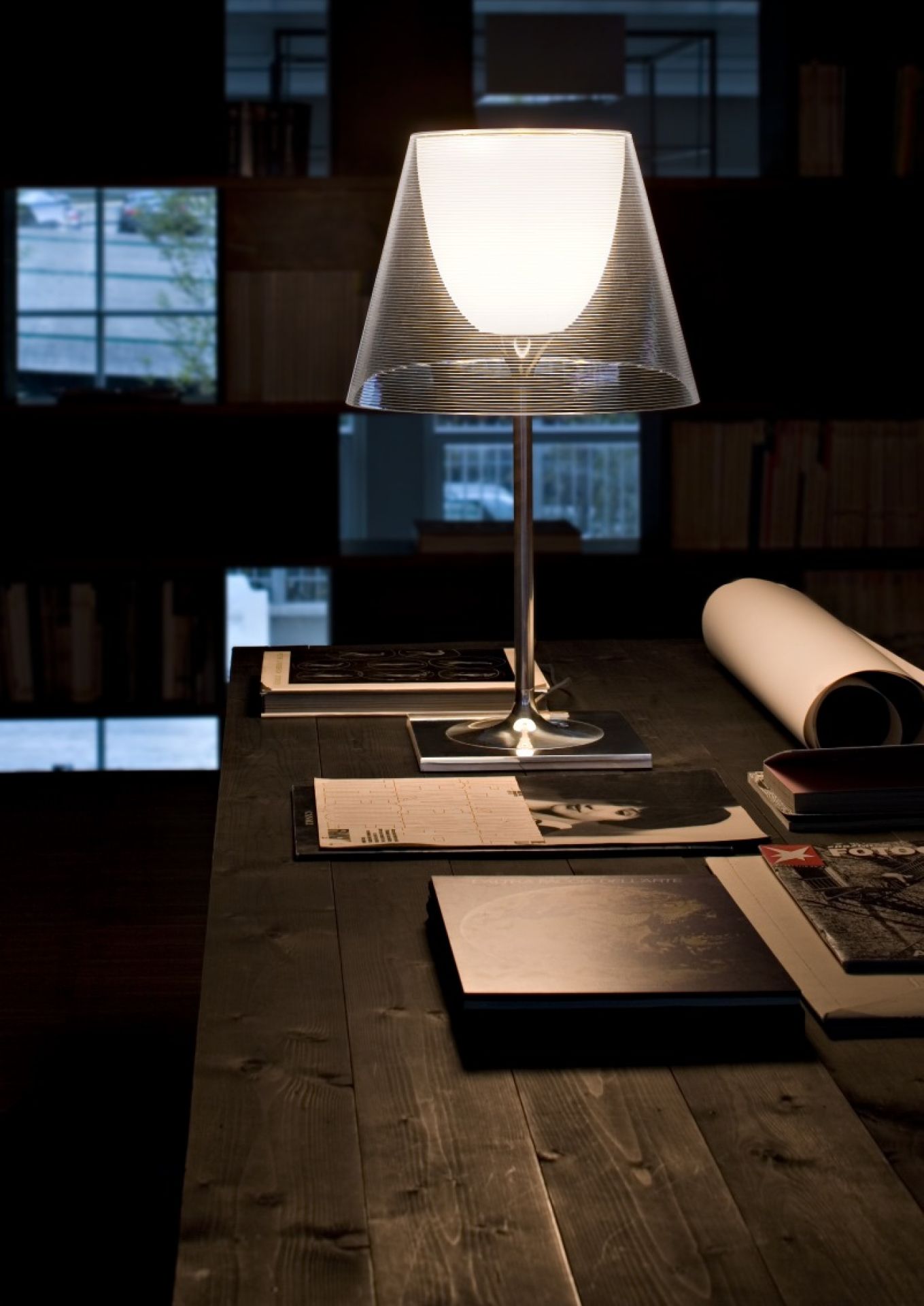 Ktribe Tischleuchte von Flos auf einem Schreibtisch, modernes Design mit transparentem Lampenschirm.