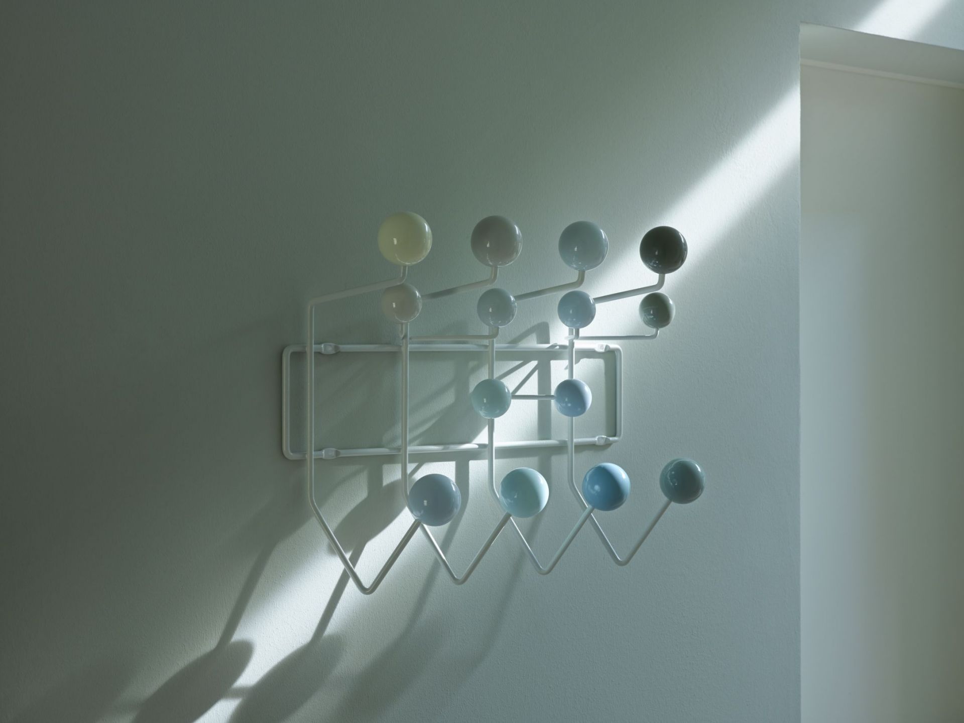 Weiße Eames Hang it all Garderobe mit bunten Kugeln an einer Wand, modernes Design.