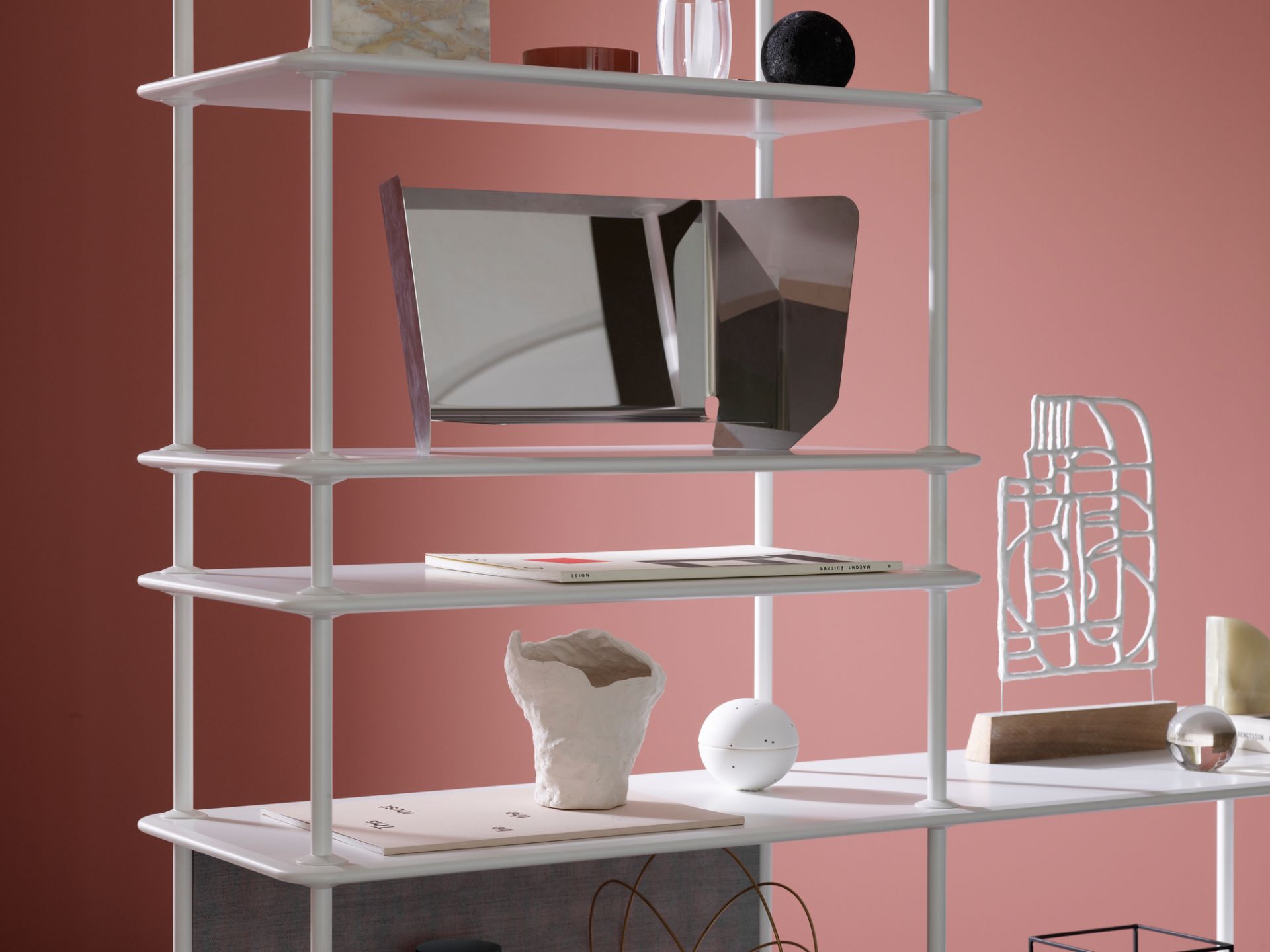 Detailaufnahme des weißen Montana Free Regals mit Deko-Elementen vor rosa Hintergrund.