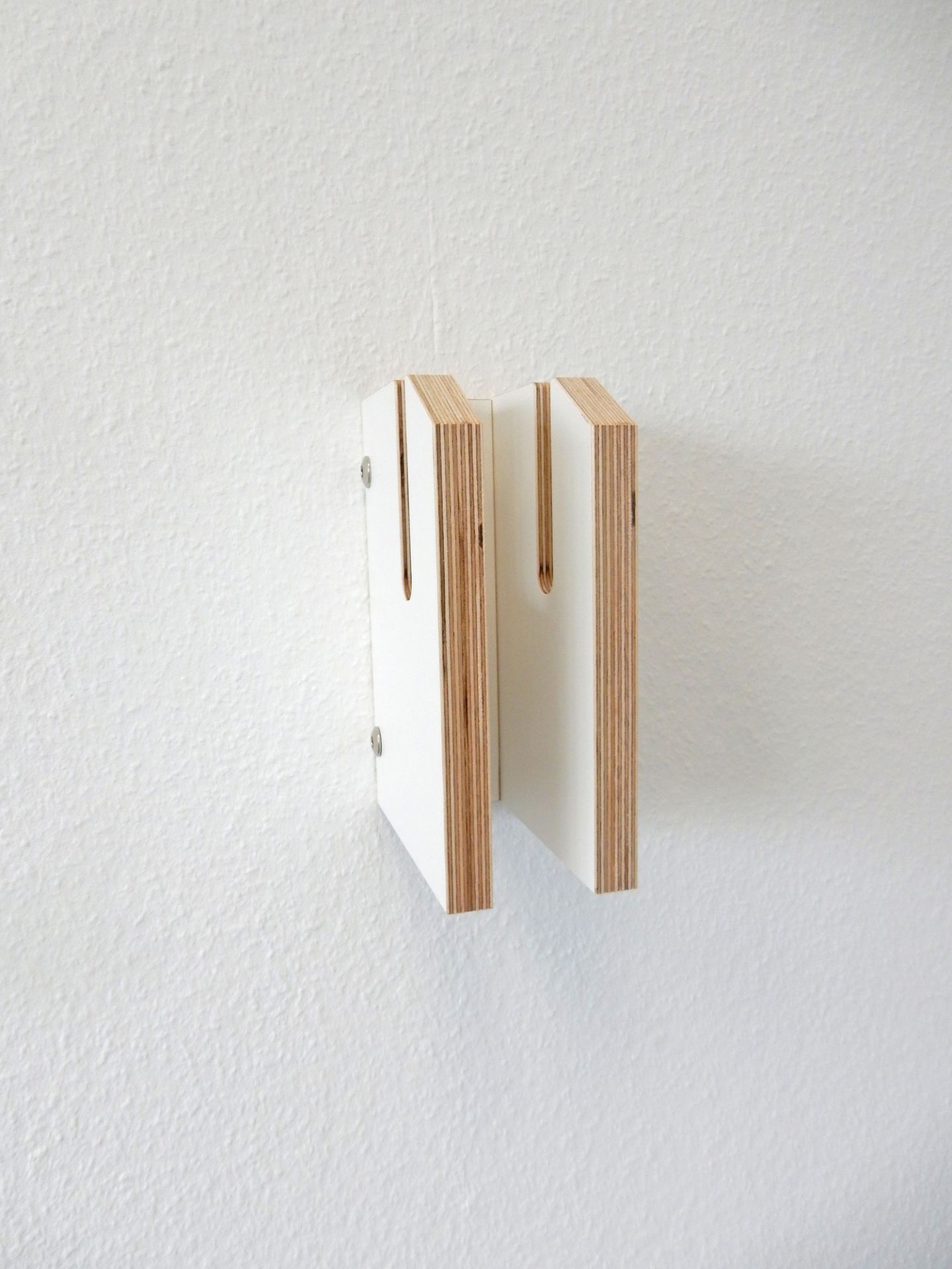 Zwei weiße Tojo Lesestoff Bücherregal-Elemente aus Holz an einer weißen Wand befestigt.