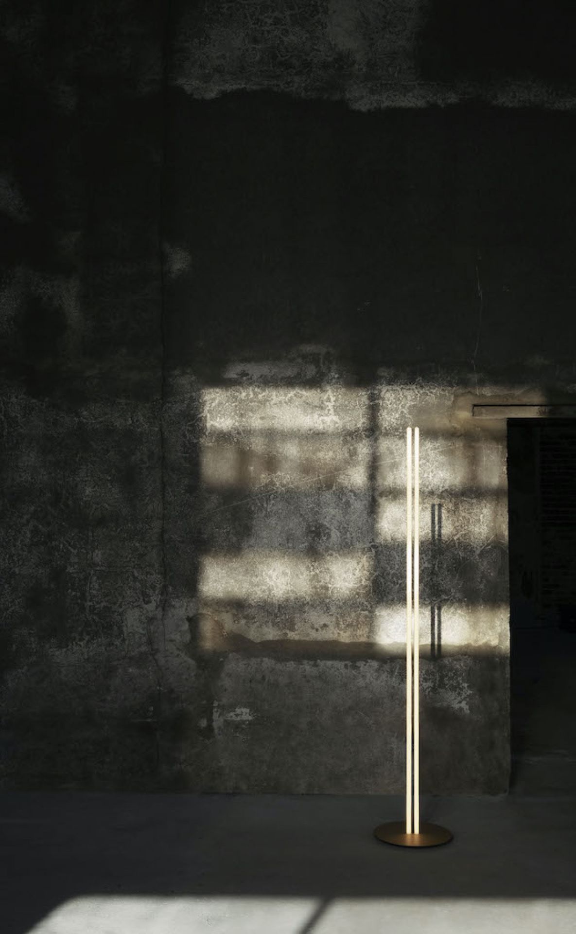 Minimalistische Coordinates LED Stehleuchte von Flos vor einer Betonwand mit Schatten. Moderne Bodenleuchte.