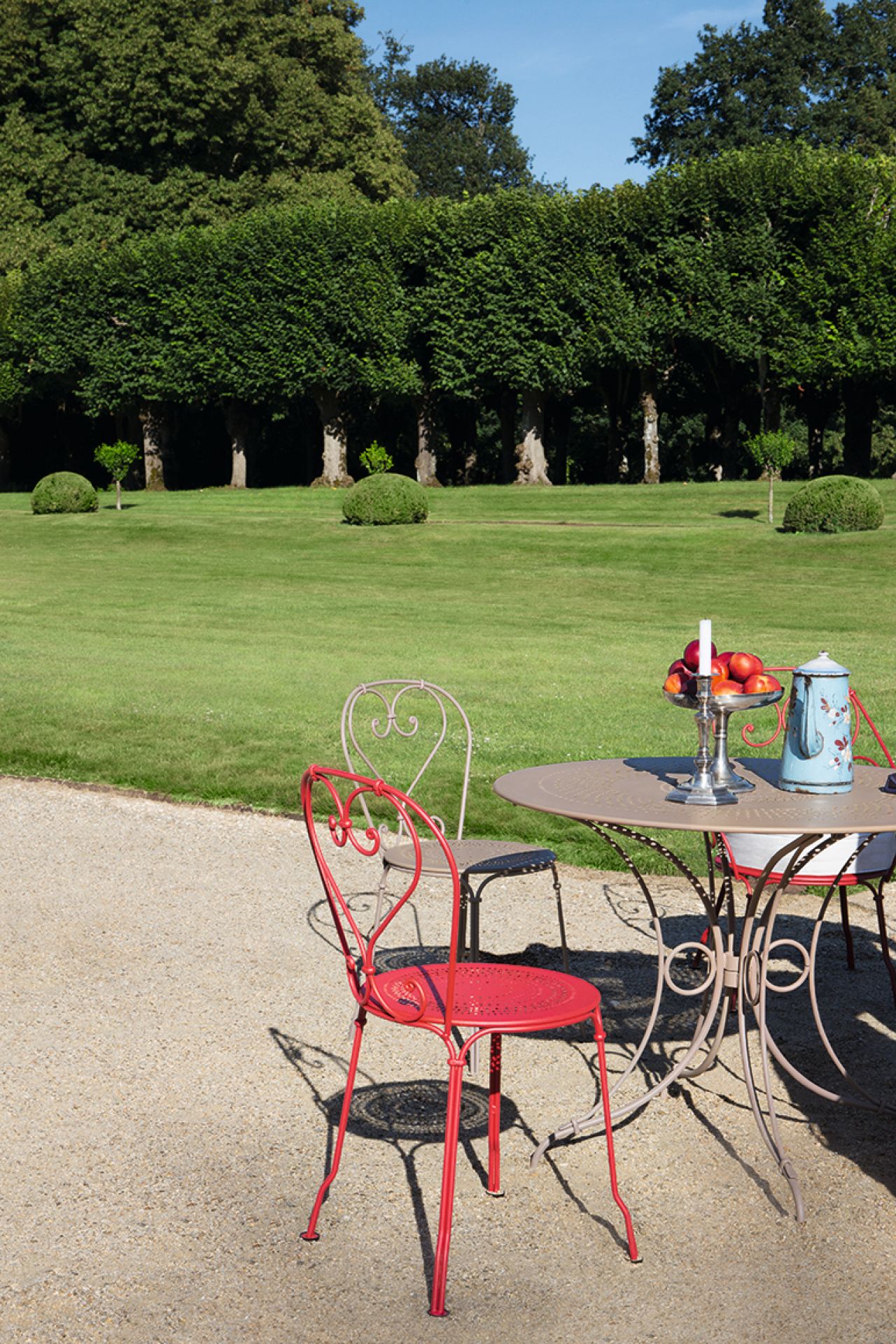 Roter Fermob 1900 Stuhl im Garten mit Tisch und Dekoration, Outdoor Möbel.