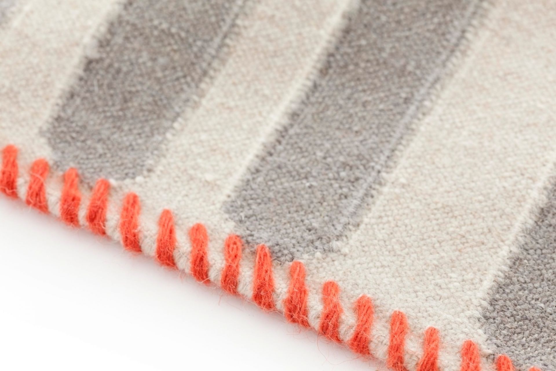 Detailaufnahme: Gestreifter Kilim Teppich mit orangefarbenem Zierstich am Rand. Hochwertiger Wollteppich für Wohnzimmer.