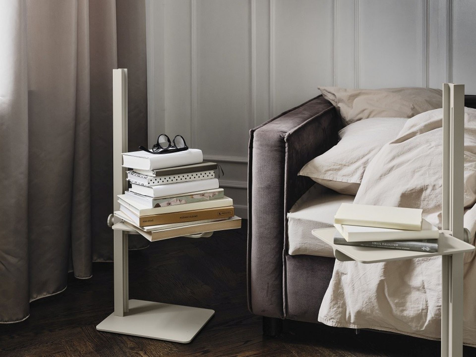 Beige Museum Sidetable Beistelltisch von String Furniture, höhenverstellbar, mit Büchern dekoriert neben einem Sofa.