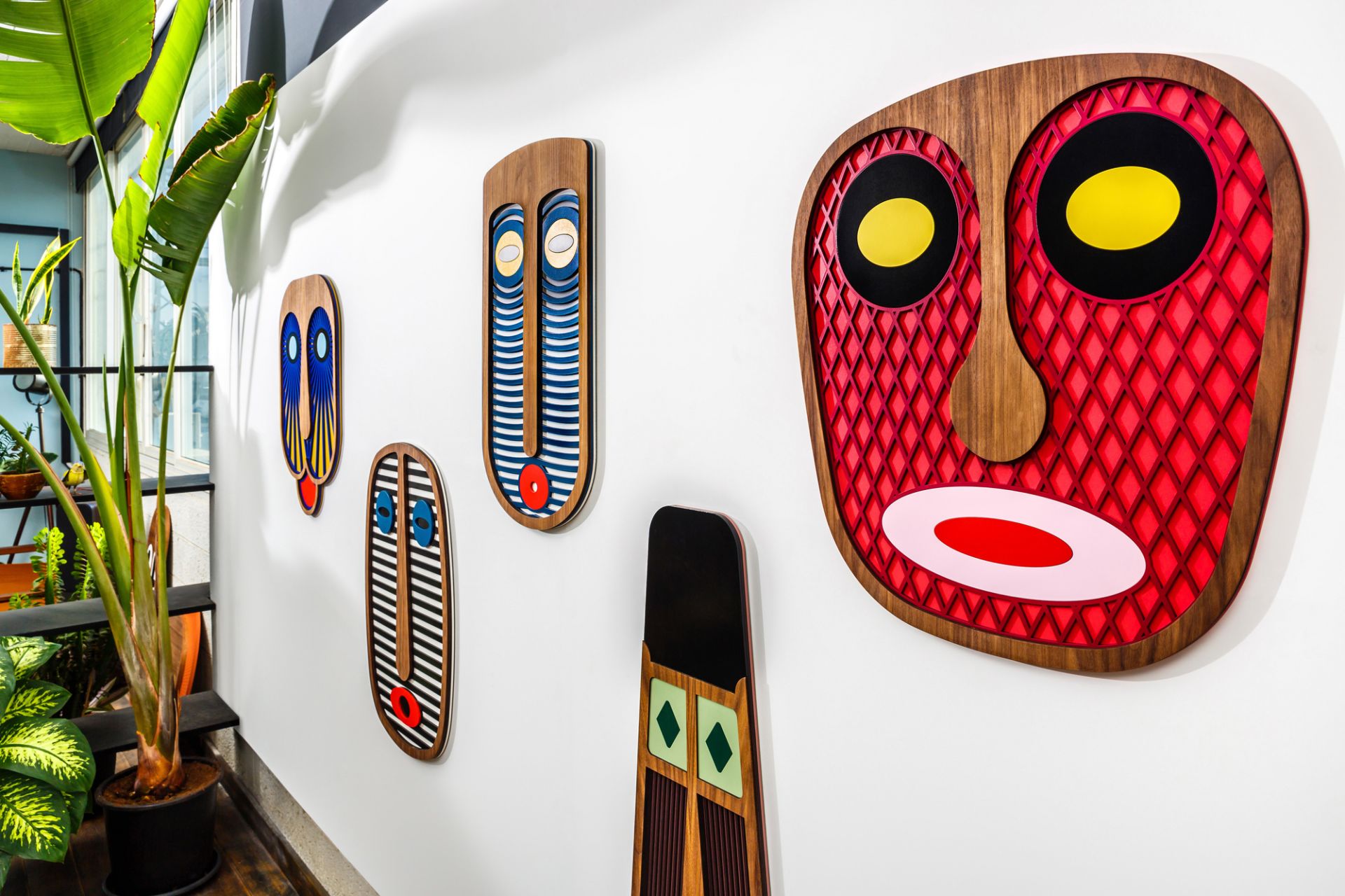 Wand mit fünf modernen, afrikanisch inspirierten Umasqu Holzmasken als Wandschmuck, Kunstobjekte für stilvolle Inneneinrichtung.