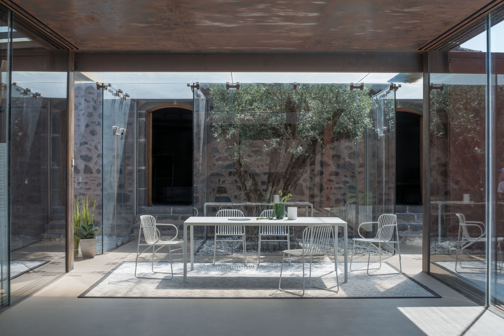 Heller Riviera Stuhl von Emu, ein moderner Gartenstuhl aus Metall, Teil einer stilvollen Essgruppe.