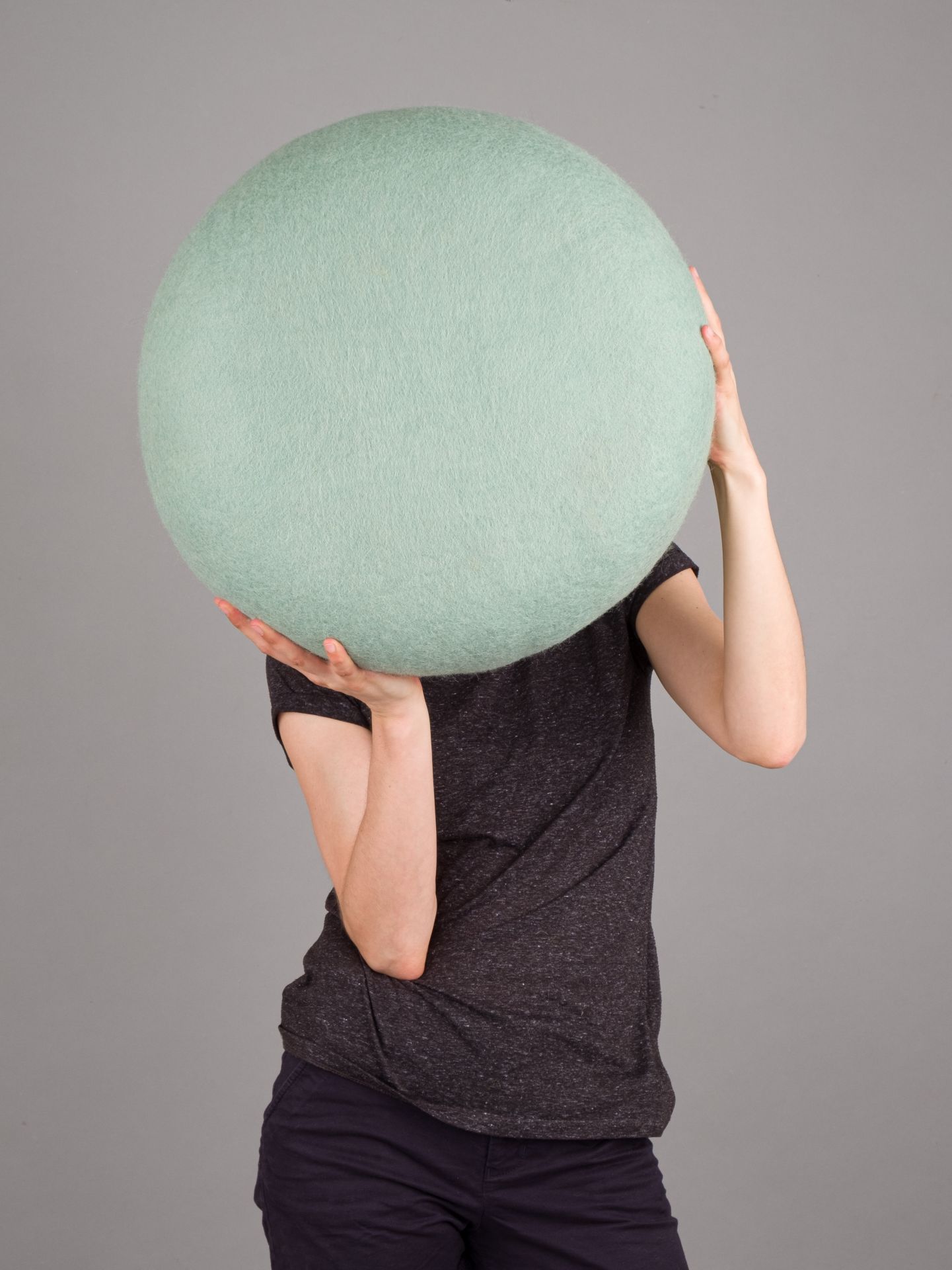 Person hält einen runden, mintgrünen Filzhocker, einen Colour Pouf von myfelt, vor dem Gesicht.